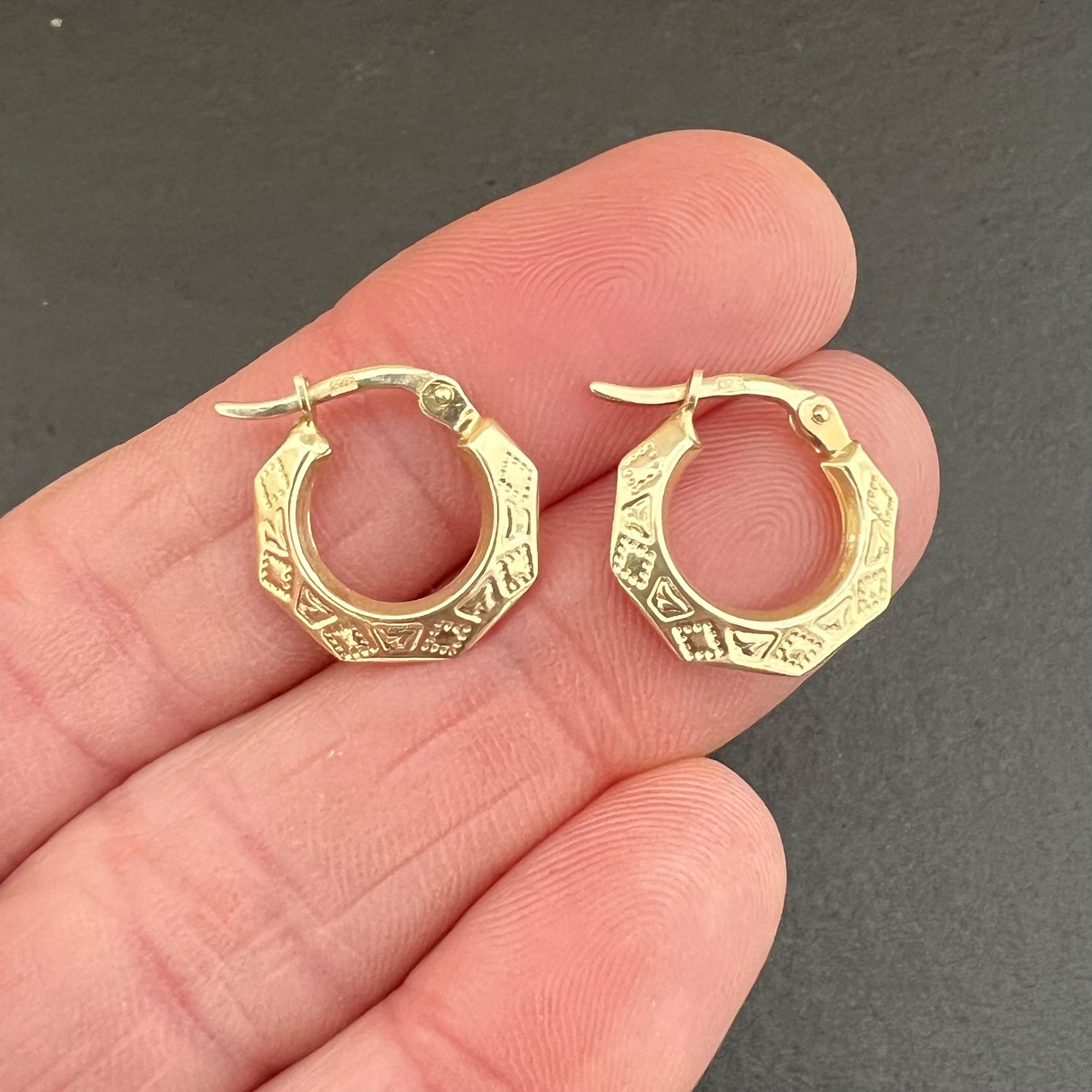A pair of vintage hoop earrings made of 14 karat yellow gold. The rounded hoops feature an engraved design that works around the piece. Hallmarks are present and visible at the hooks.

They are a great size (15 mm diameter) and super lightweight