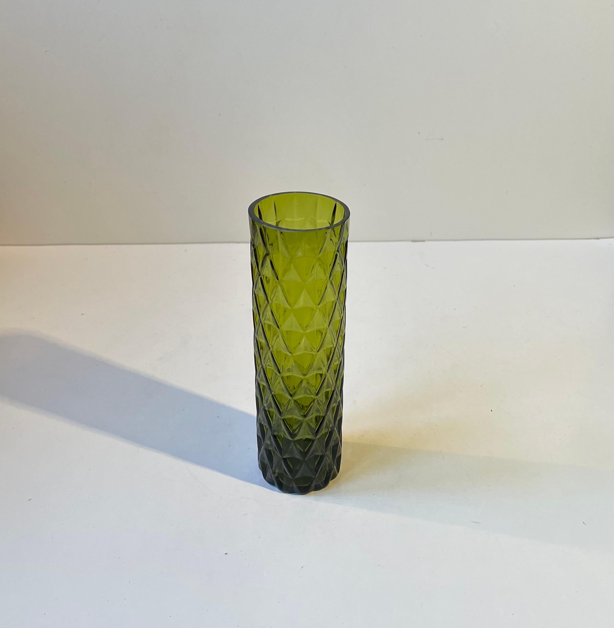 Un élégant vase cylindrique en verre moulé teinté vert émeraude. Motif de haut en bas avec des flèches/diamants. Le verre 