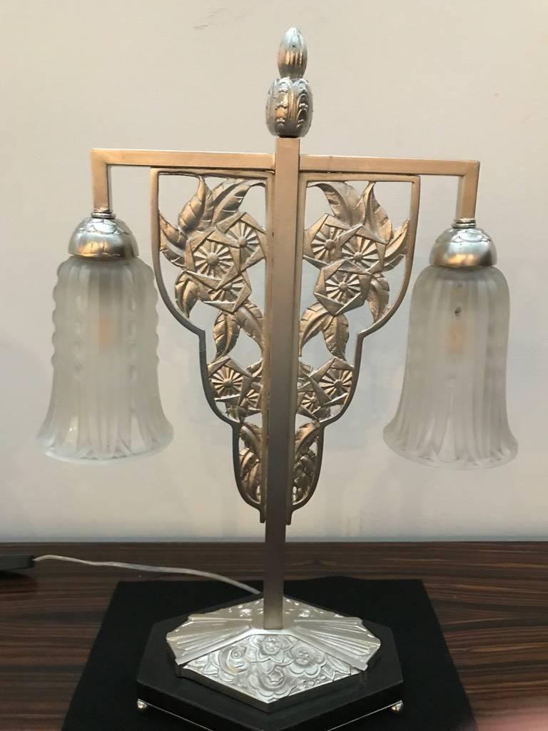 French Art Deco table lamp by Georges Leleu. Having two shades in frosted glass with polished details having geometric motif. Held by a silvered bronze geometric and floral base sitting on marble. Has been rewired for American use having two