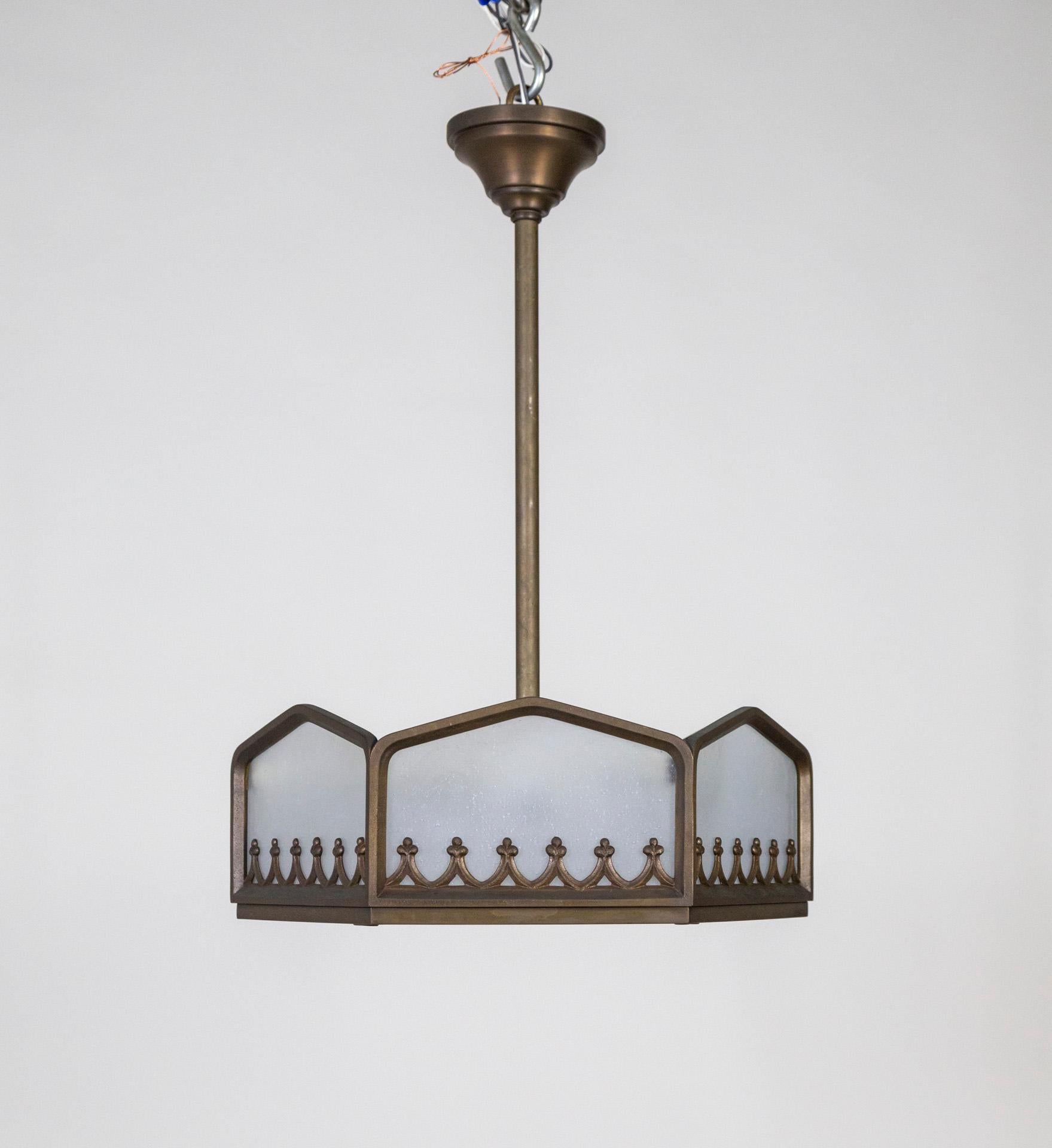 A cast, darkened brass, six sided frame holding poured glass panels, including a bottom diffuser. The structure has a weighty, wrought iron look; with scrolls and foliate. The glass is frosted and seeded. Beautifully proportioned, with a timeless