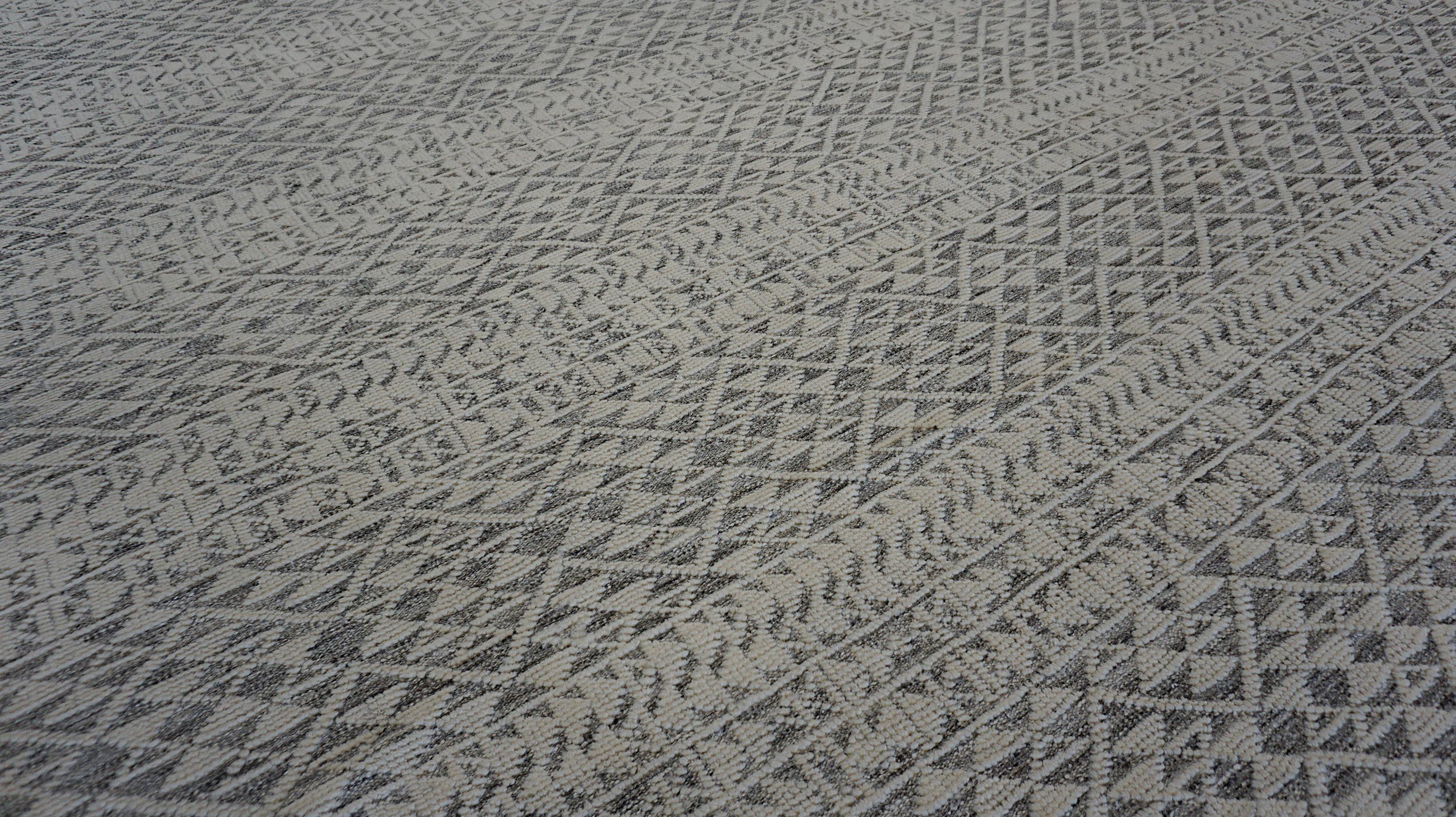 Esta alfombra de lana anudada a mano presenta una cautivadora mezcla de estética tribal y sofisticación moderna. Elaborada por hábiles artesanos con lana hilada a mano, esta alfombra presenta un patrón geométrico meticulosamente tejido,