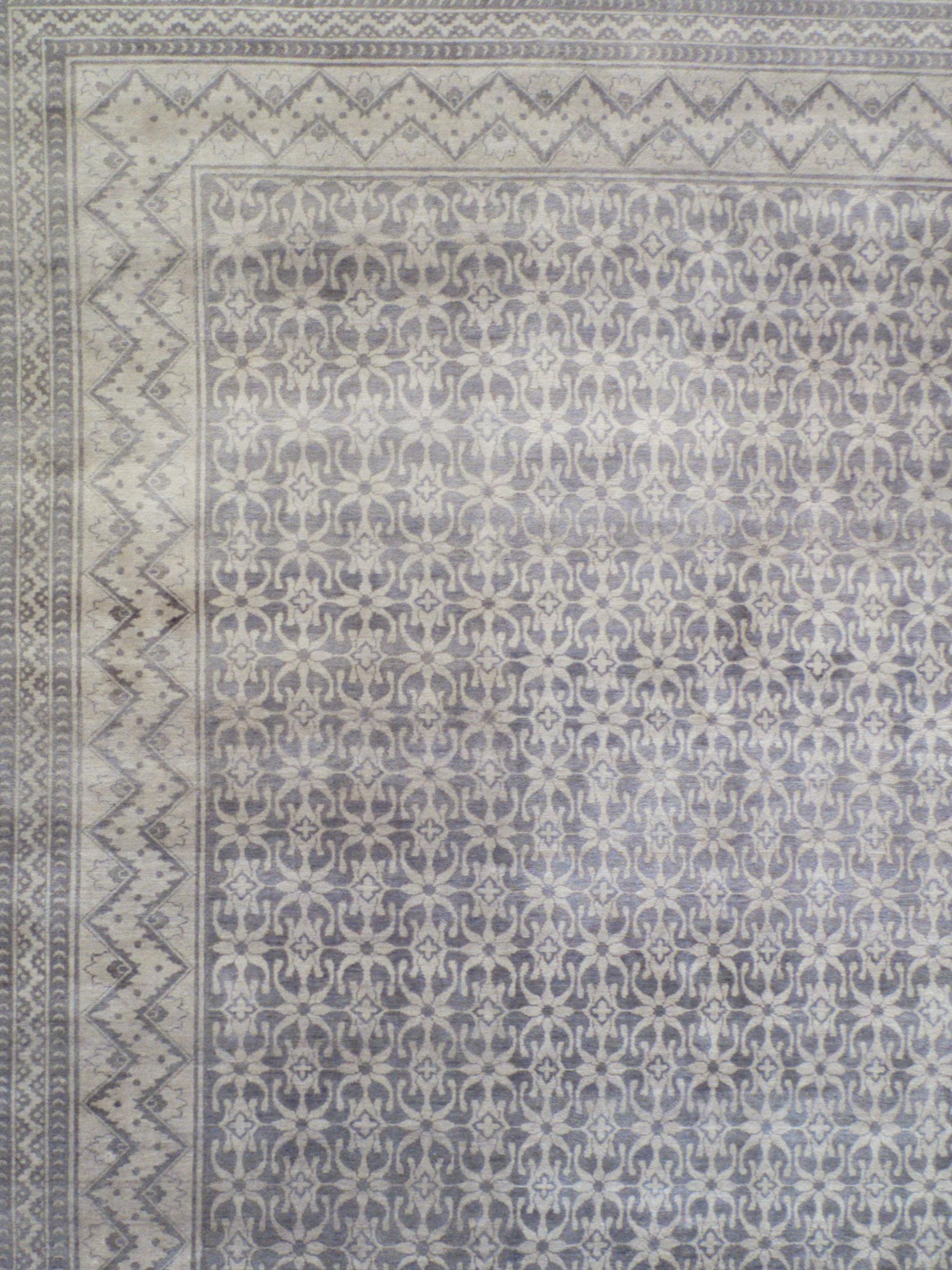 In soft and versatile shades of gray and steel blue wool, this hand-knotted carpet measures 8’10” x 11’10” and features a repetitive and transitional all-over pattern.  The carpet's design illustrates a flourishing gray flower garden, detailed in