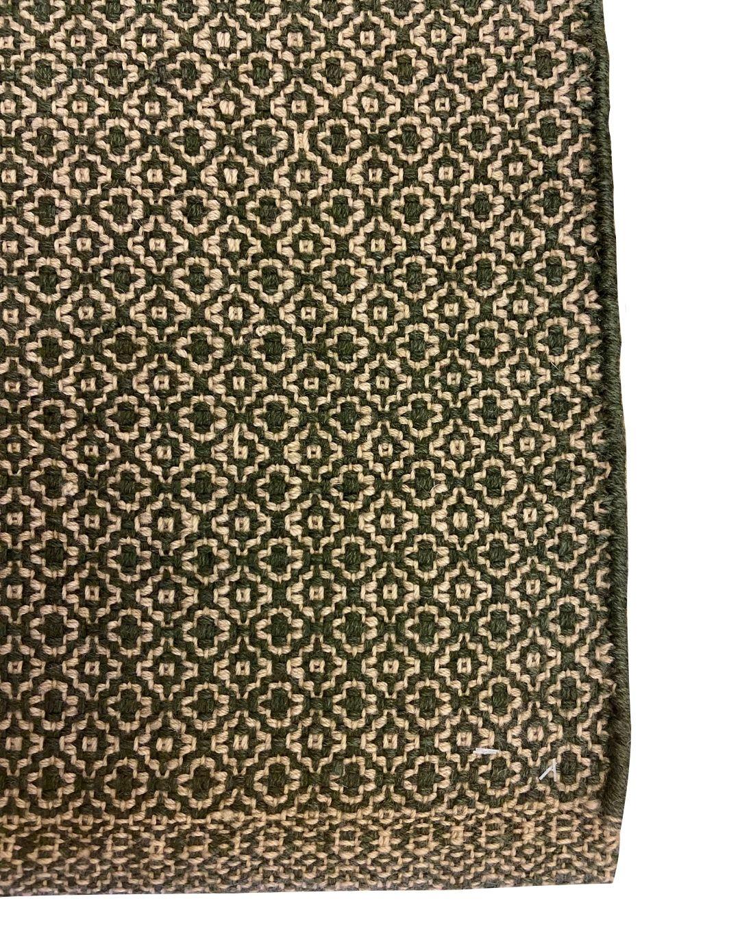 Questo tappeto moderno organico a trama piatta in lana verde e crema, che misura 2' x 4', è un'incredibile miscela di semplicità e intricatezza. Il tappeto presenta un sofisticato motivo geometrico che aggiunge una texture sottile ma accattivante a