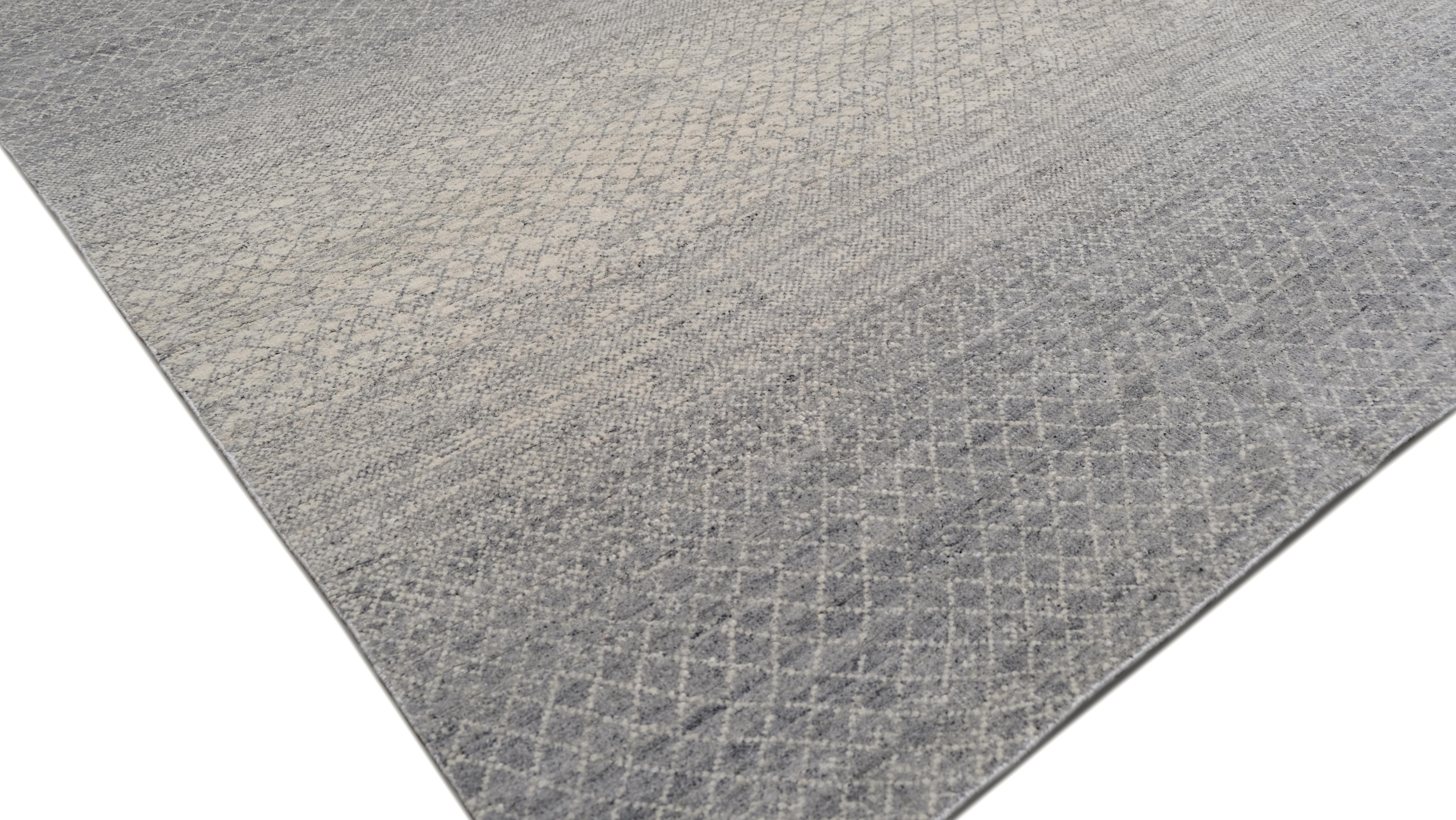 Verschönern Sie Ihr Interieur mit der raffinierten Raffinesse dieses handgeknüpften Wollteppichs, der ein subtiles geometrisches Farbverlaufsdesign aufweist. Das komplizierte Rautengittermuster geht nahtlos in sanfte Grau- und Elfenbeintöne über und