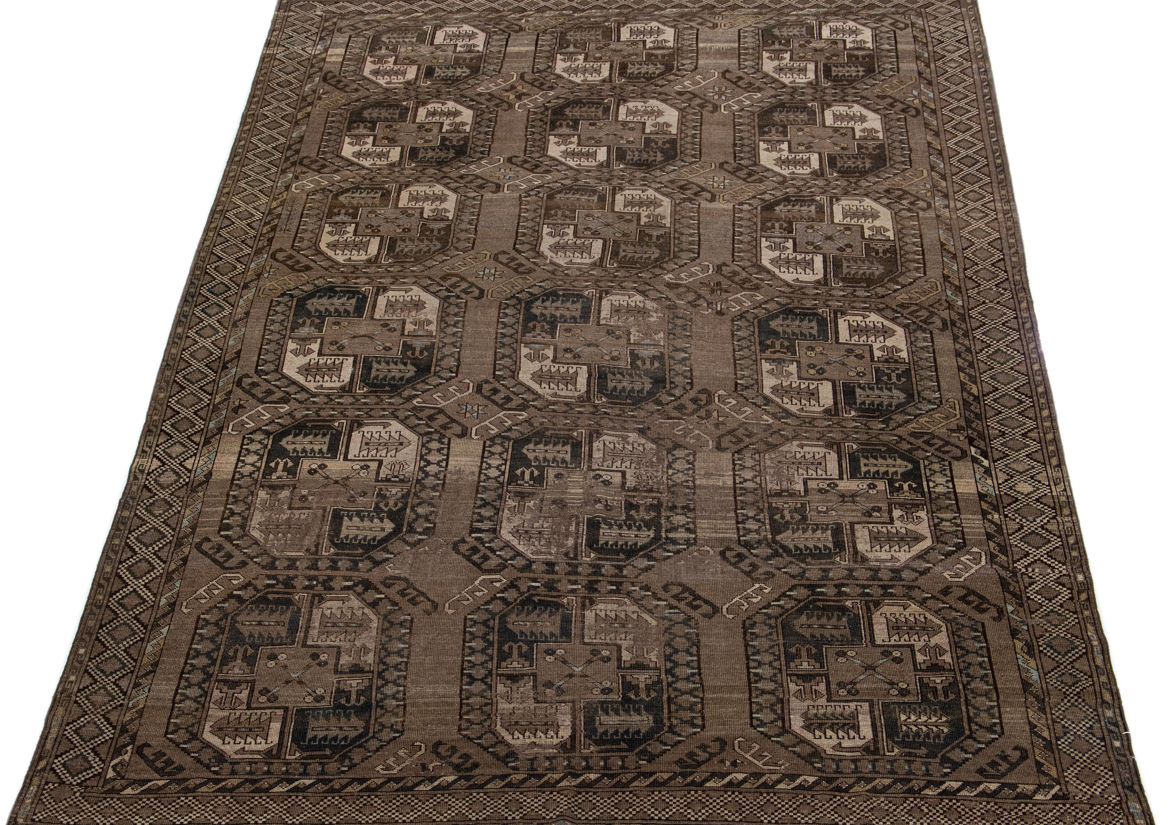 Beautiful antique Turkmen hand-knotted wool rug with a brown color field. This Persian piece has a gorgeous Gul pattern design in beige and blue.

This rug measures: 7'1