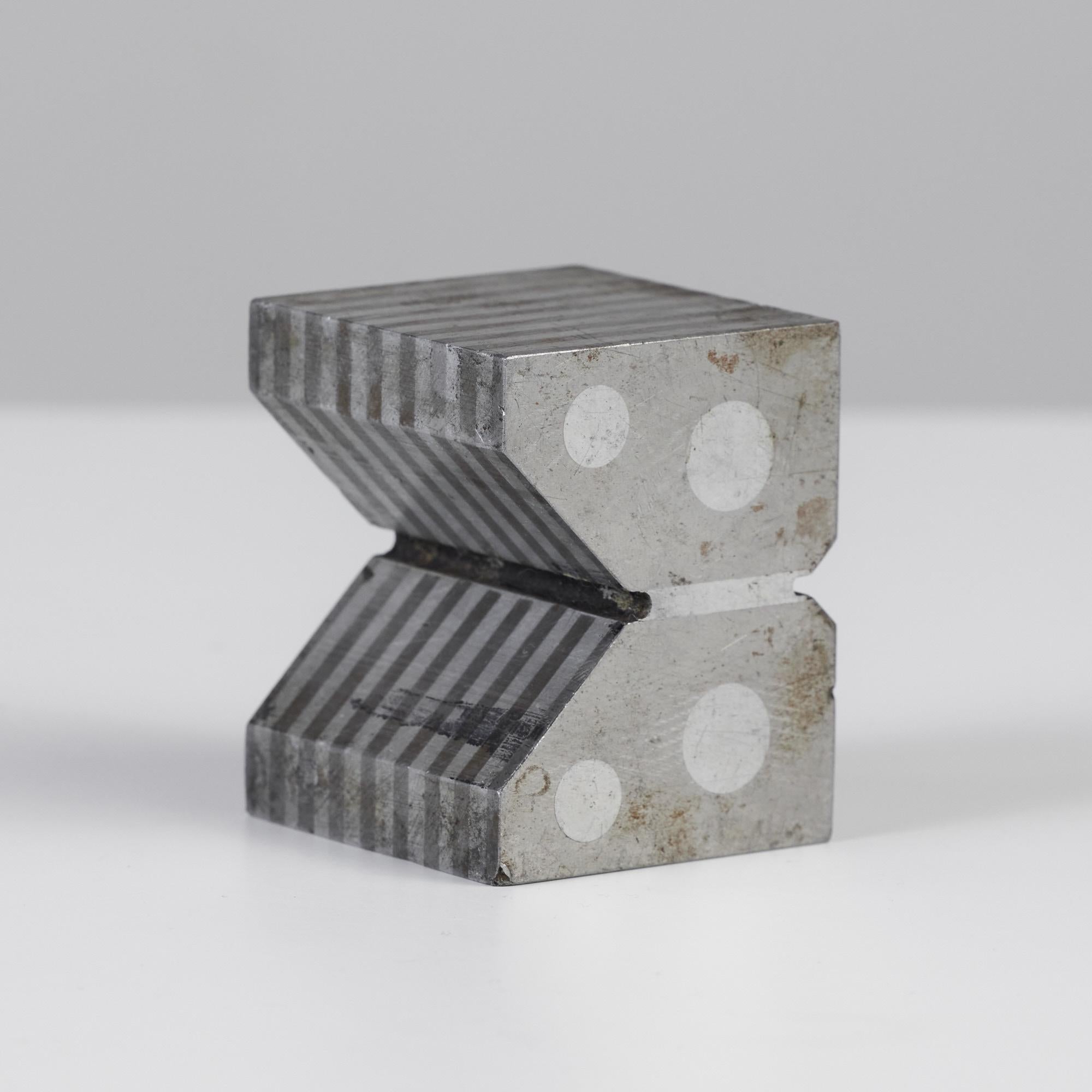 Industrial machine block brutalist form featuring alternating striations along the sides with four steel dots on either end. The geometric block can be used as bookends or as a decorative element.

Sold individually; two available.