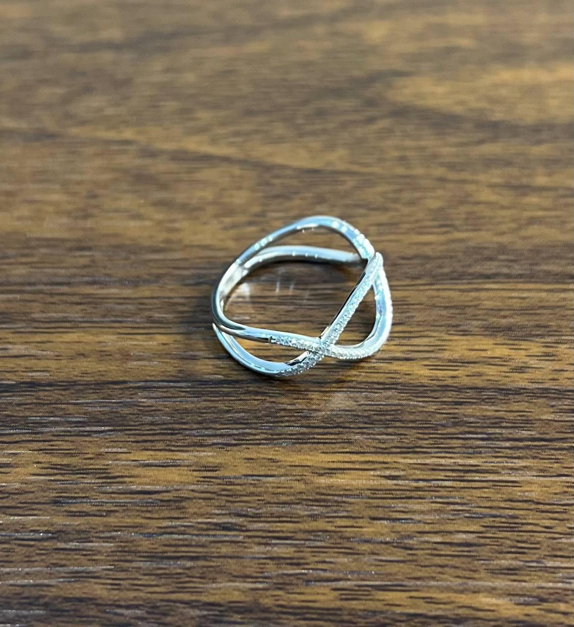 A modern and elegant ring featuring an open, crisscross design with delicate pavé-set diamonds. The ring showcases a sleek, minimalist style with intersecting bands that create a unique geometric pattern. Crafted in a polished metal, this