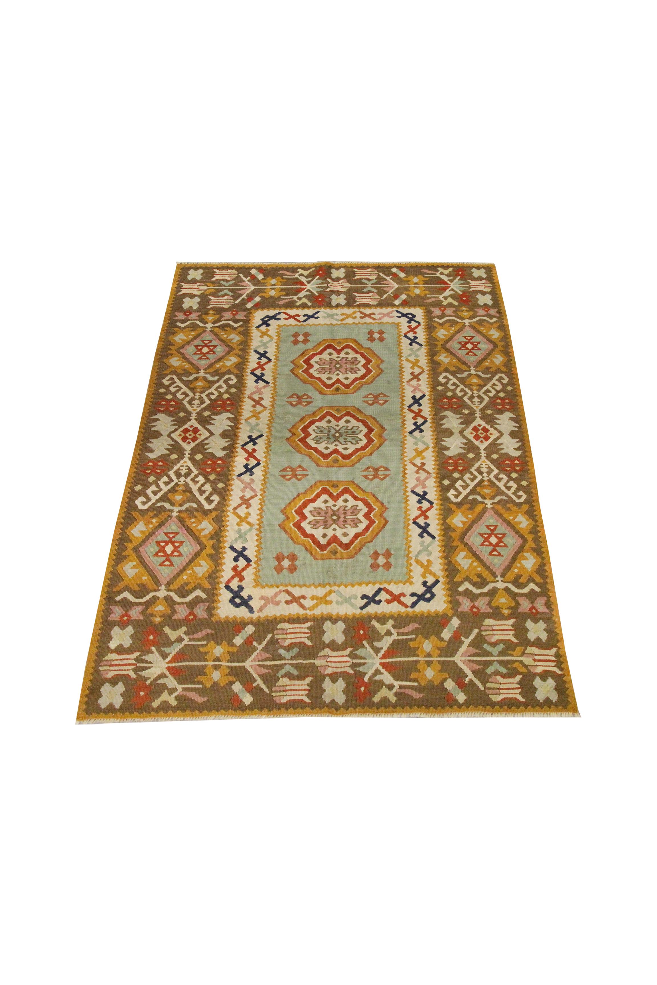 Symmetrical and sophisticated, this Oriental Turkish Kilim has been woven in Pirot with a bold geometric design. The central design features a blue background with mustard, pink and red accents that make up the trio of motifs that run through the