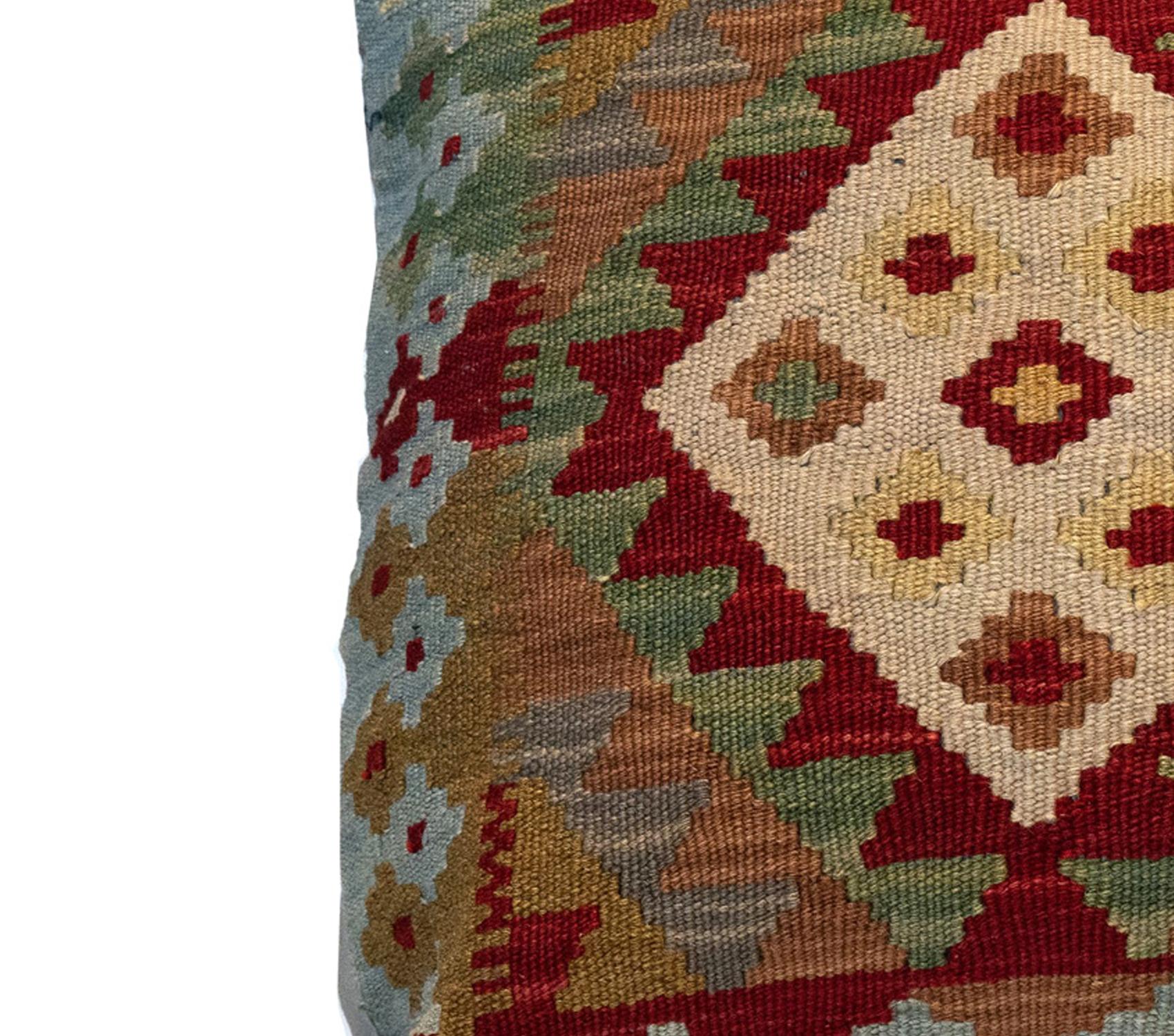 This fantastic cushion has been woven by hand using traditional kilim weaving techniques with hand-spun wool. Featuring a symmetrical geometric pattern woven in beautiful rustic colours. Including olive green, beige-brown and rust red. These elegant
