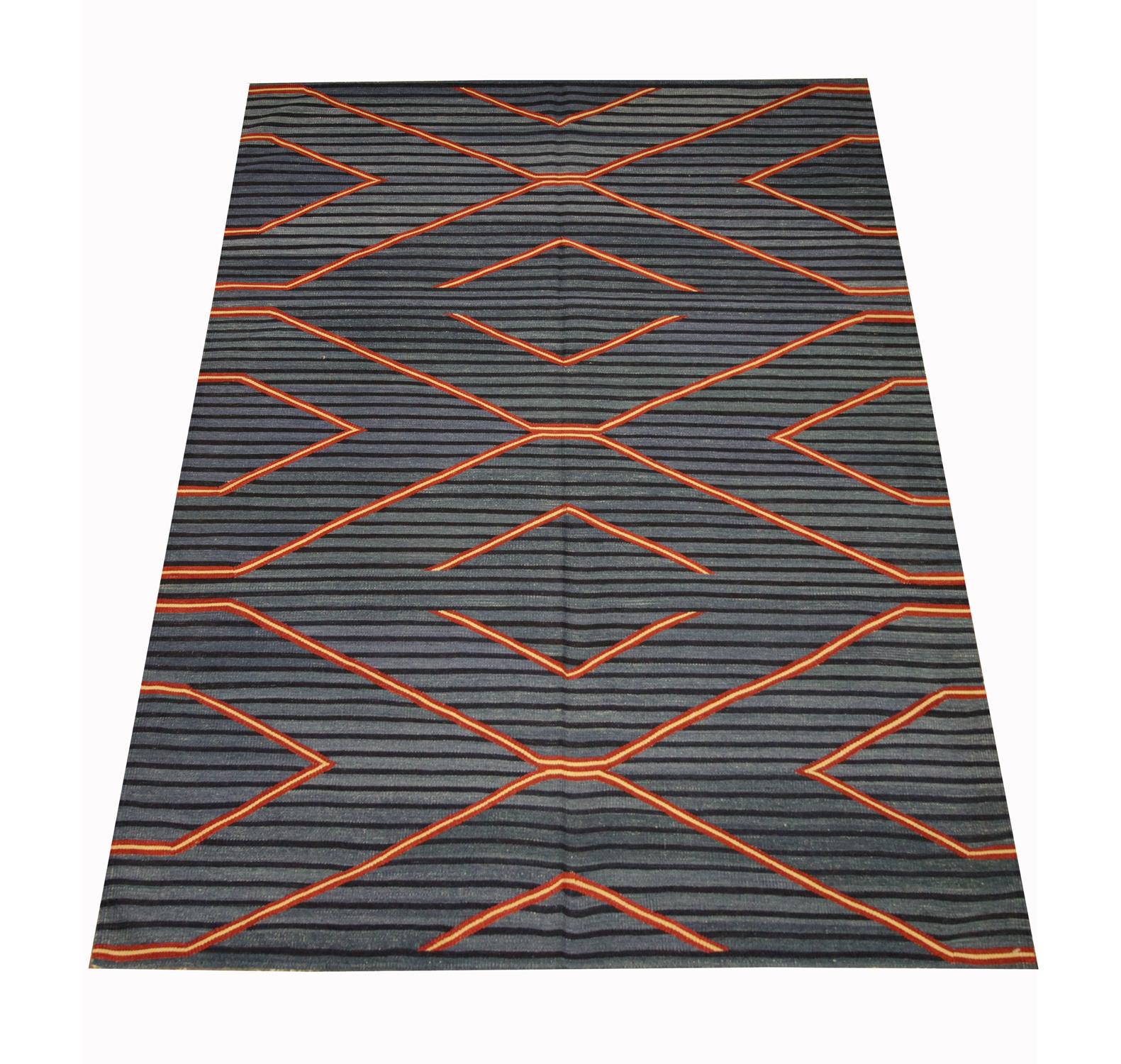 This elegant rug is a modern kilim rug woven by hand with traditional techniques and materials. The design features a striped black and blue pattern with accents of red and beige that make up the interwoven geometric design. The simple colour