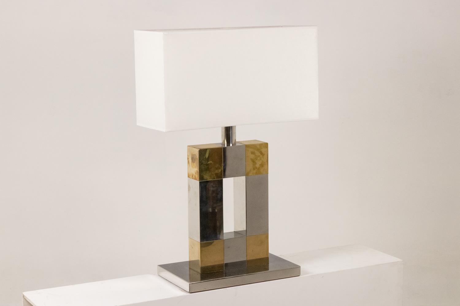 Lampe géométrique en métal argenté et doré, ajourée au centre, avec sa base rectangulaire. Abat-jour de forme rectangulaire.

Œuvre italienne réalisée dans les années 1970.

Dimensions : H 77 x L 40,5 x P 24 cm : H 77 x L 40,5 x P 24 cm

Référence :