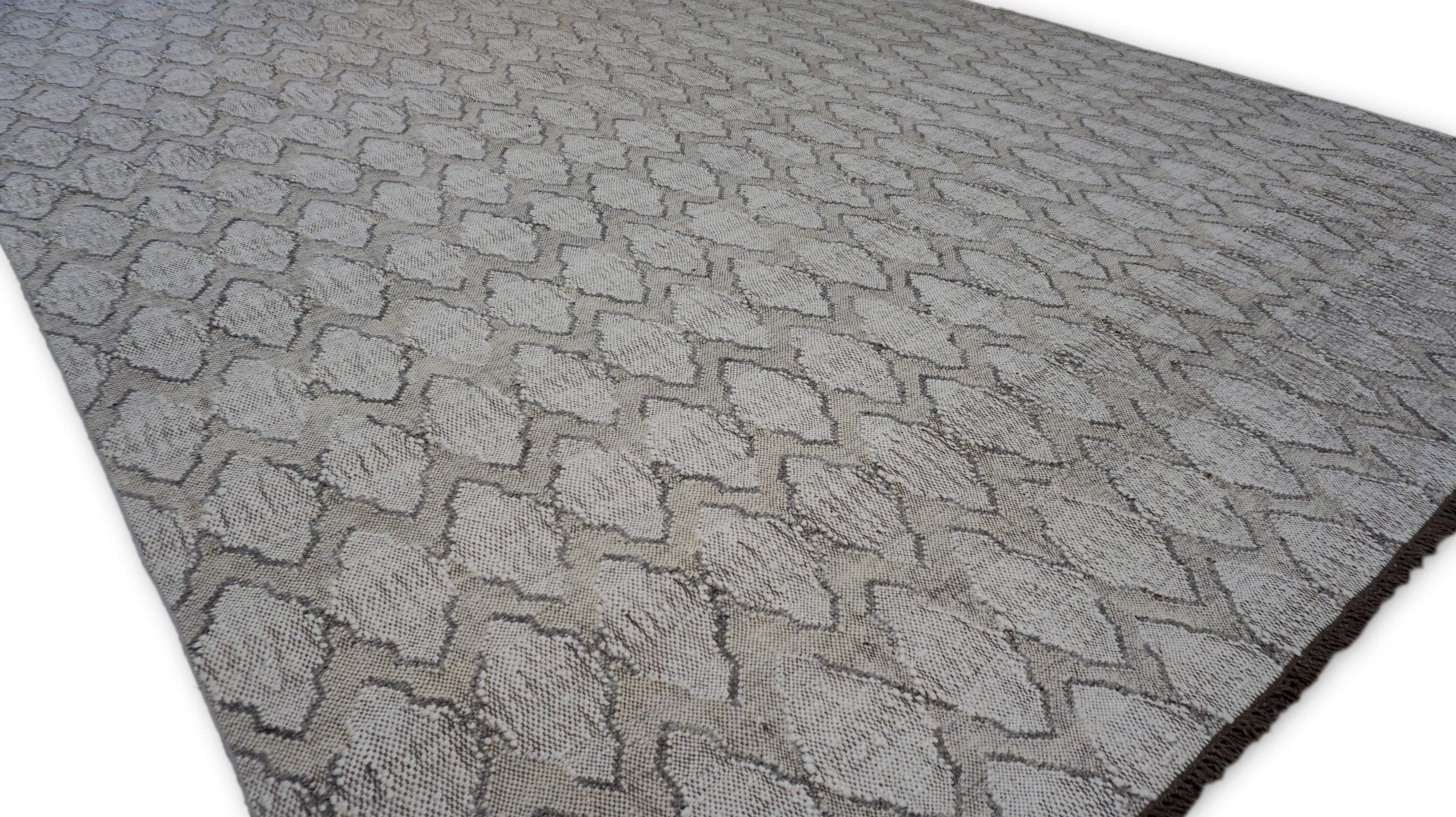 This flatweave wool rug features a sophisticated geometric lattice pattern, meticulously woven in a neutral gray, tan, Ivory and taupe palette. The raised and recessed weave creates a dimensional texture, enhancing the visual depth and tactile
