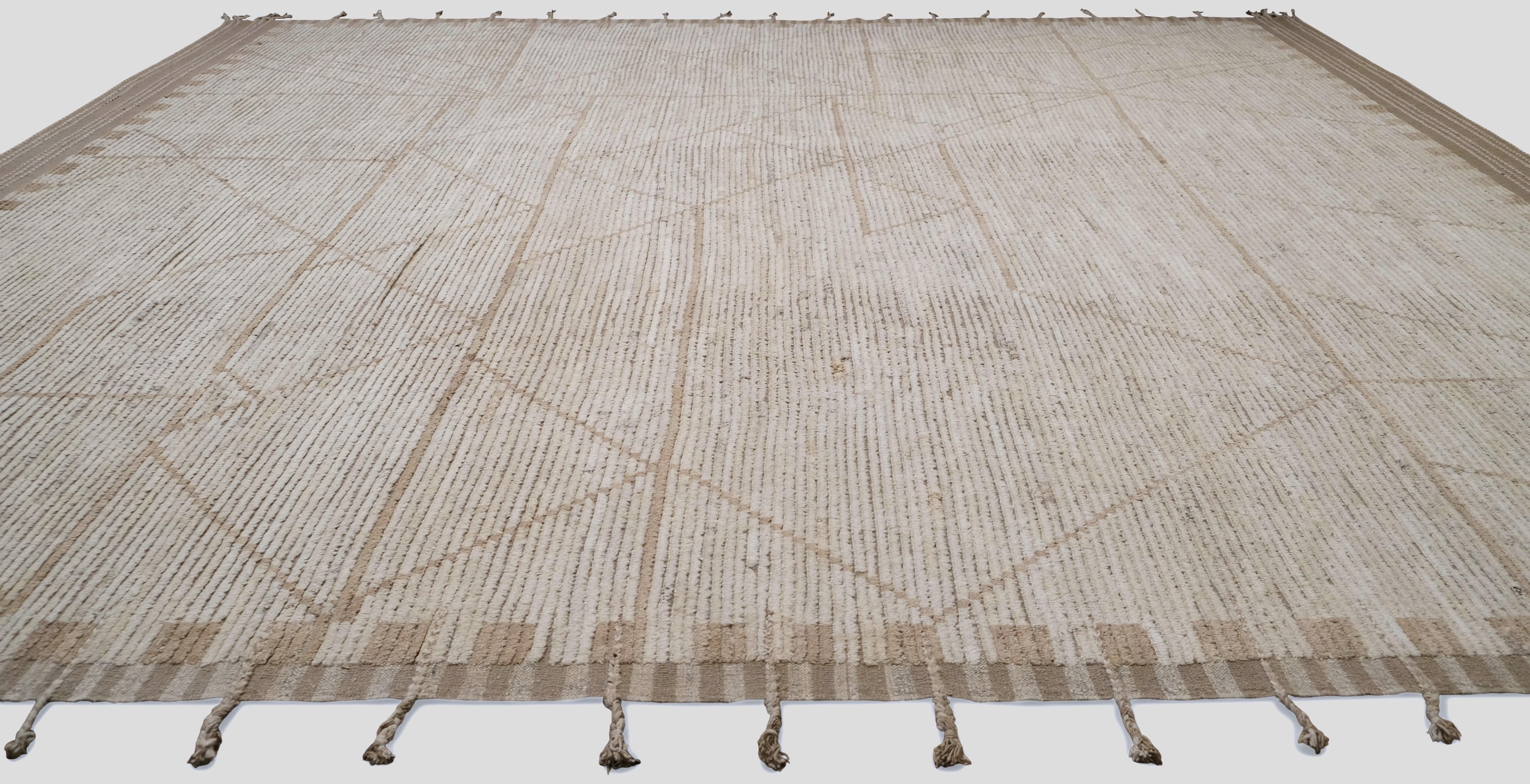 Dieser handgeknüpfte Wollteppich zeichnet sich durch ein auffälliges geometrisches Linienmuster vor einem strukturierten, neutral getönten Hintergrund aus. Die sanfte Beige- und Taupe-Farbpalette sorgt für eine subtile, aber dennoch raffinierte