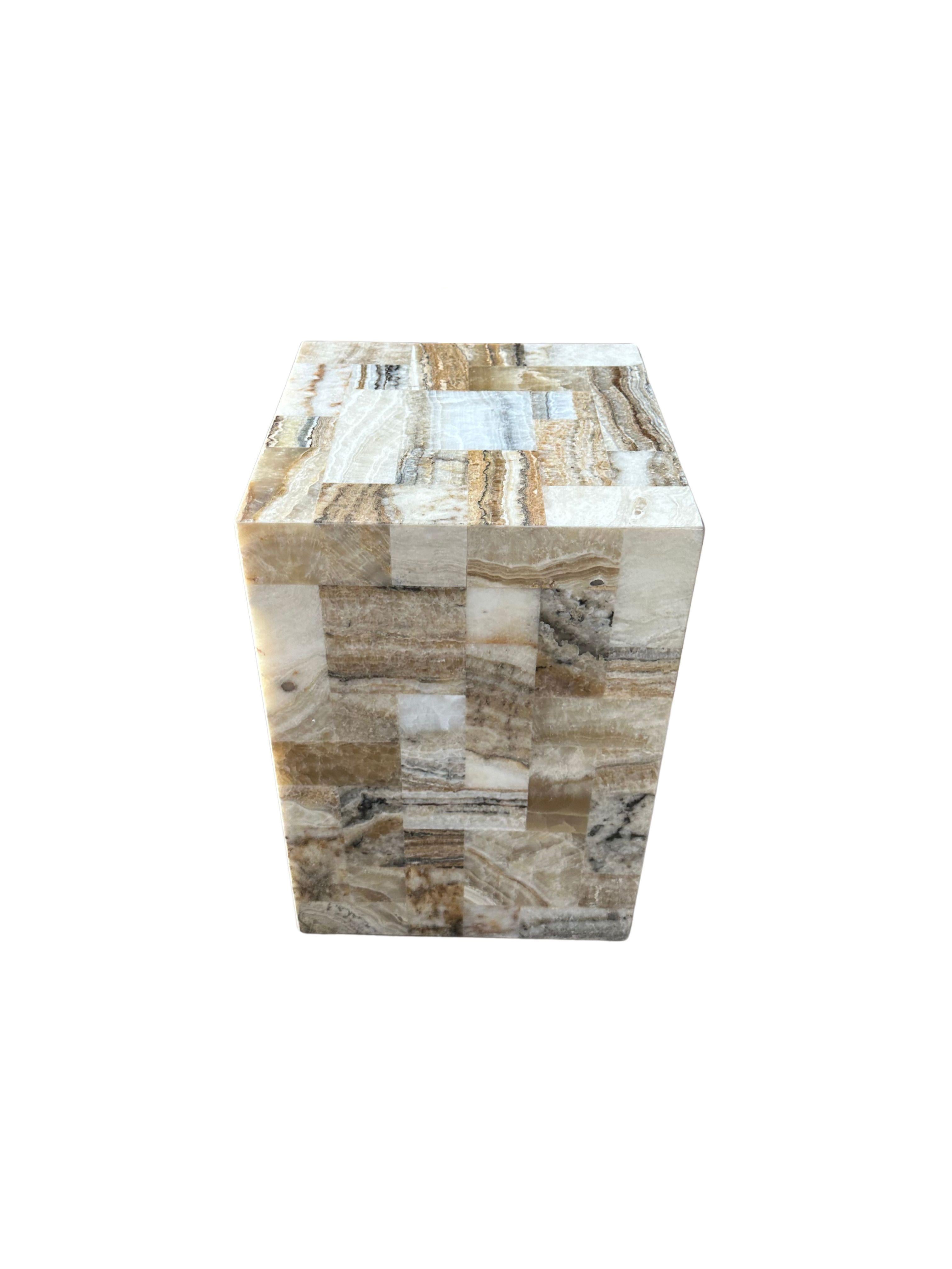 A marble side table or pedestal with wonderful textures and shades. It features a geometric patterning, with smaller marble cut outs that have been molded together. Hand-crafted by local artisans on the island of Java, this is a wonderful object to