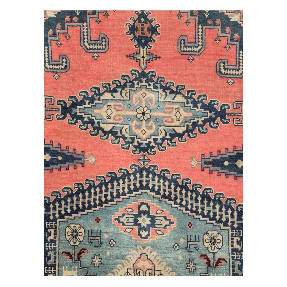 A vintage Persian Veece large room size carpet handmade during the mid-20th century with a large scale geometric design and border in shades of blue over a light red and coral field.

Measures: 10' 3