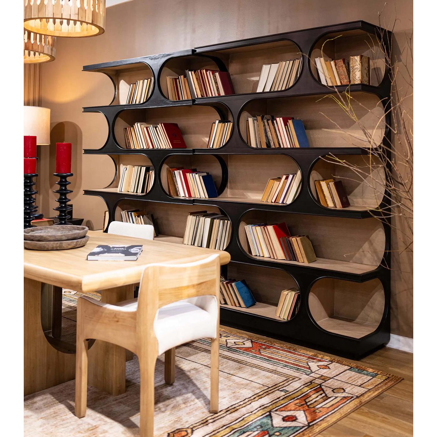 Rifinita in nero Batavia con interni in finitura Sandbar, questa libreria presenta ritmiche aperture ovali a forma di mezzaluna che formano una silhouette architettonica, un omaggio alla sperimentazione scultorea del modernismo degli anni
