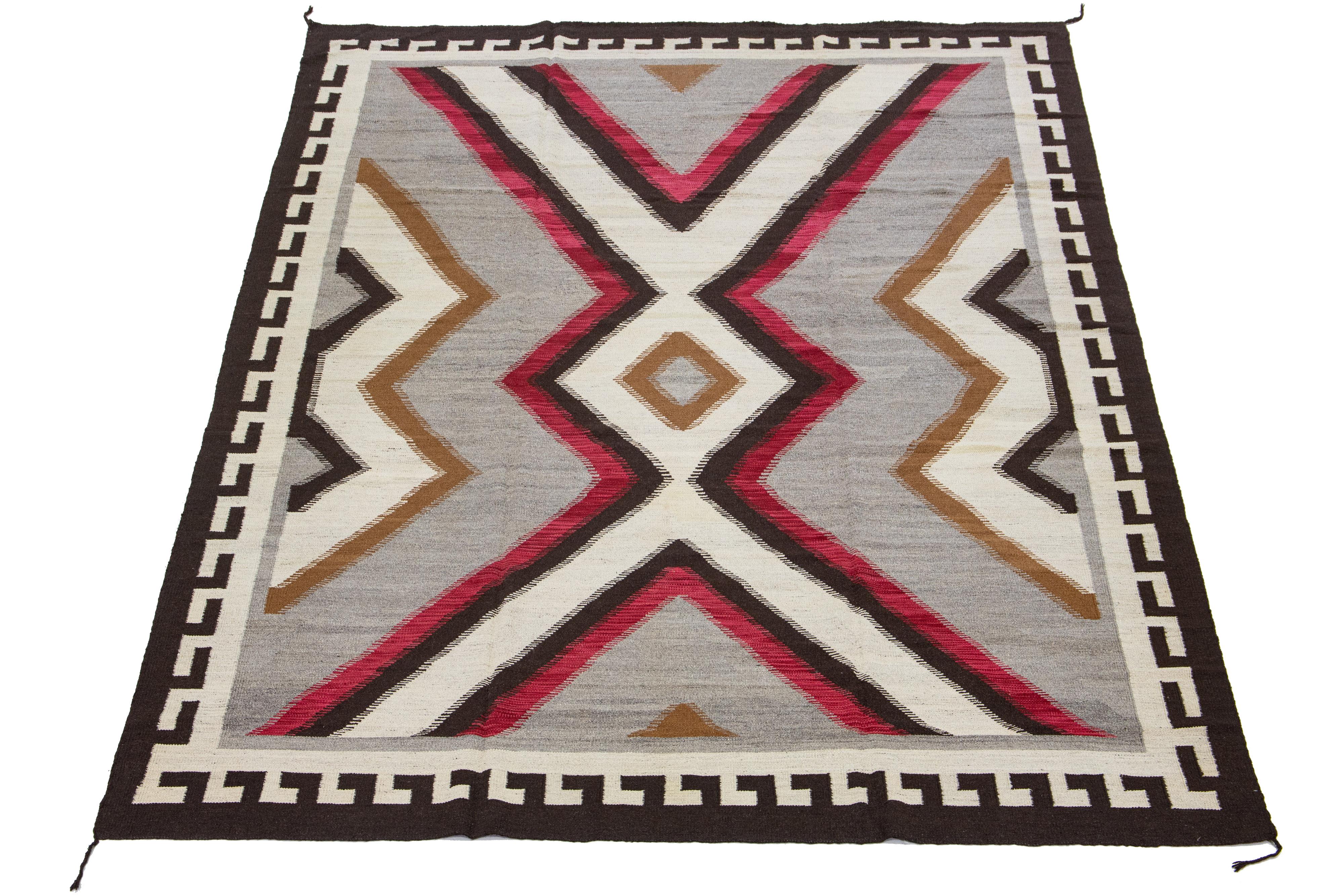 Beautiful contemporary handmade flat-weave Navajo-style wool rug with a gray field. This piece has beige, brown, and red accents in an all-over geometric design.

This rug measures 10'2