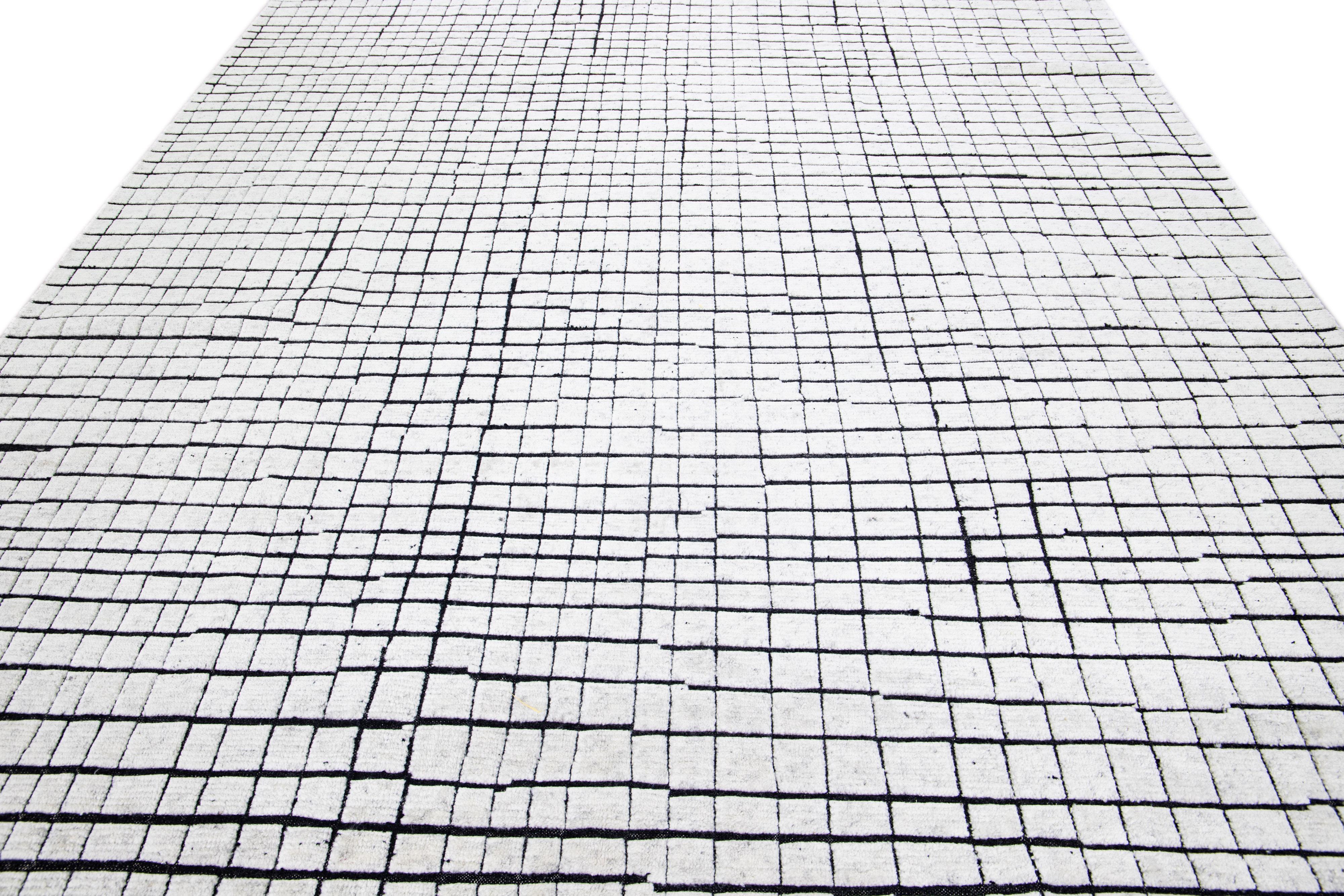 Beautiful Moroccan-Style handmade wool rug with a white field. This Moroccan rug has black accents in a gorgeous all-over geometric pattern design.

This rug measures: 9'1