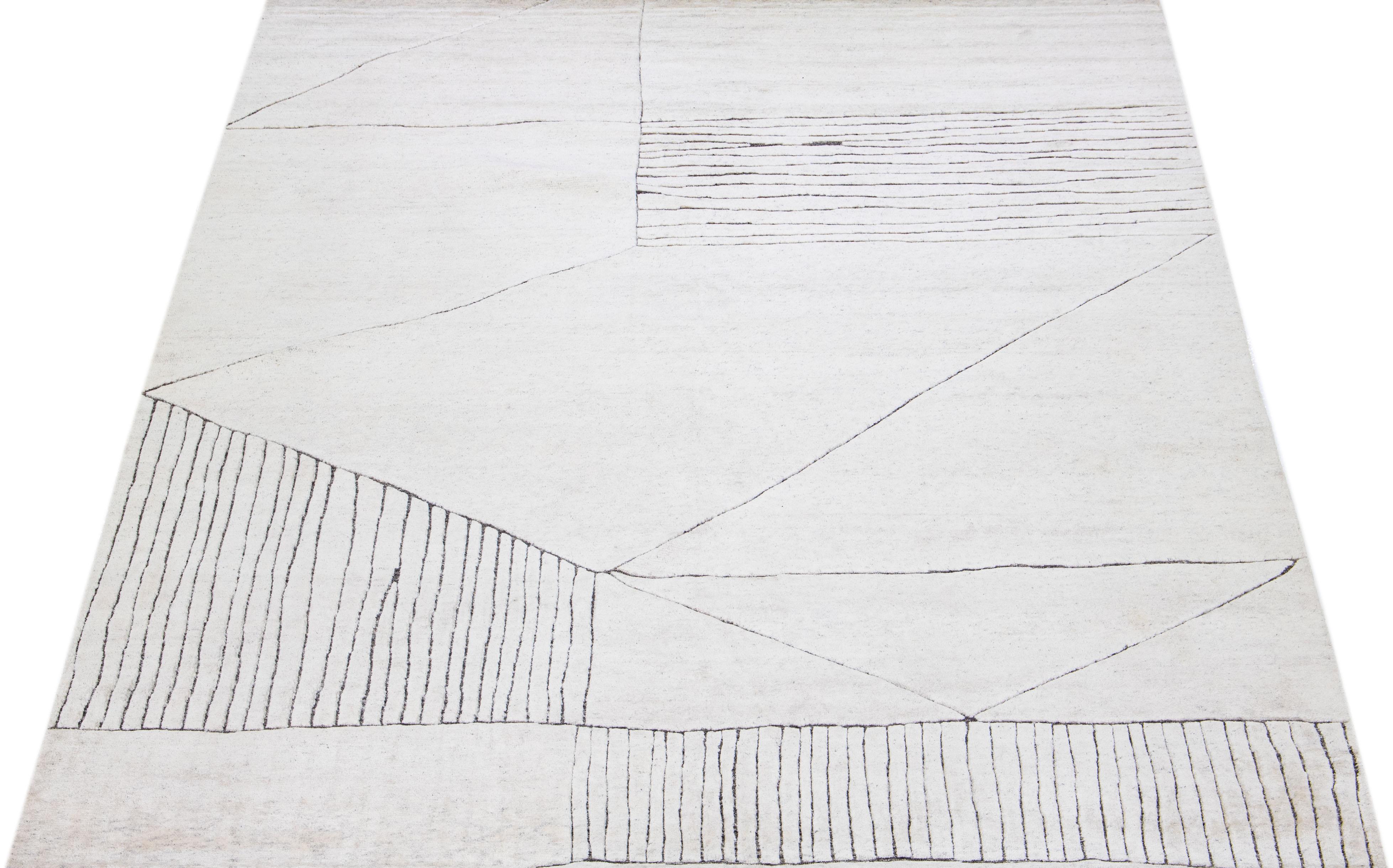Schöner moderner, handgeknüpfter Wollteppich im marokkanischen Stil mit elfenbeinfarbenem Farbfeld. Dieser Teppich gehört zur Safi Collection'S von Apadana und zeichnet sich durch ein geometrisches Muster in Grau aus.

Dieser Teppich misst: 10'1