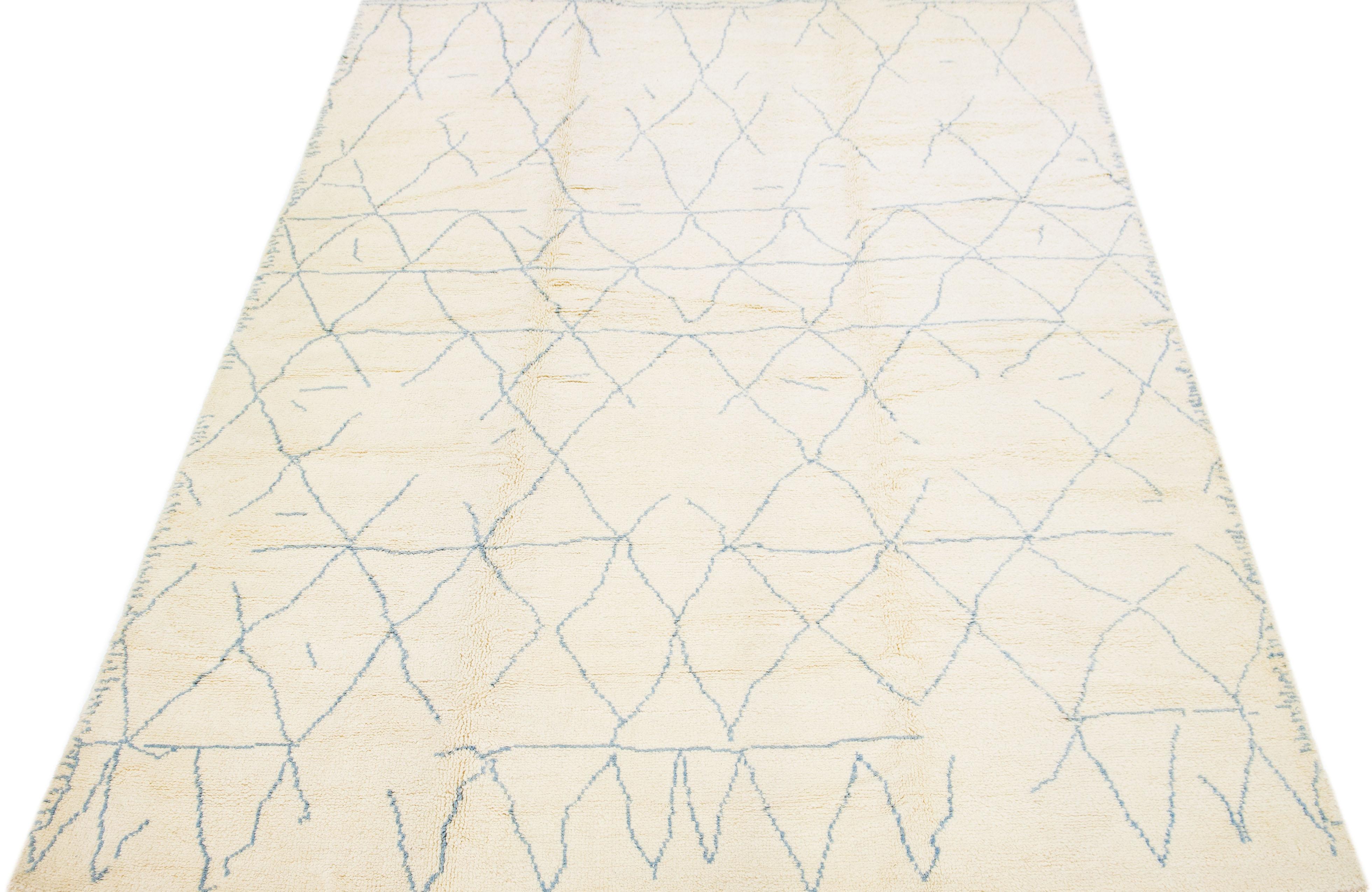 Bring a touch of luxury to your home with our exquisite hand knotted wool rug. Boasting a modern abstract motif, its beige field is contrasted with tantalizing blue hues, creating an enchanted Moroccan pattern. This area rug is ideal for a