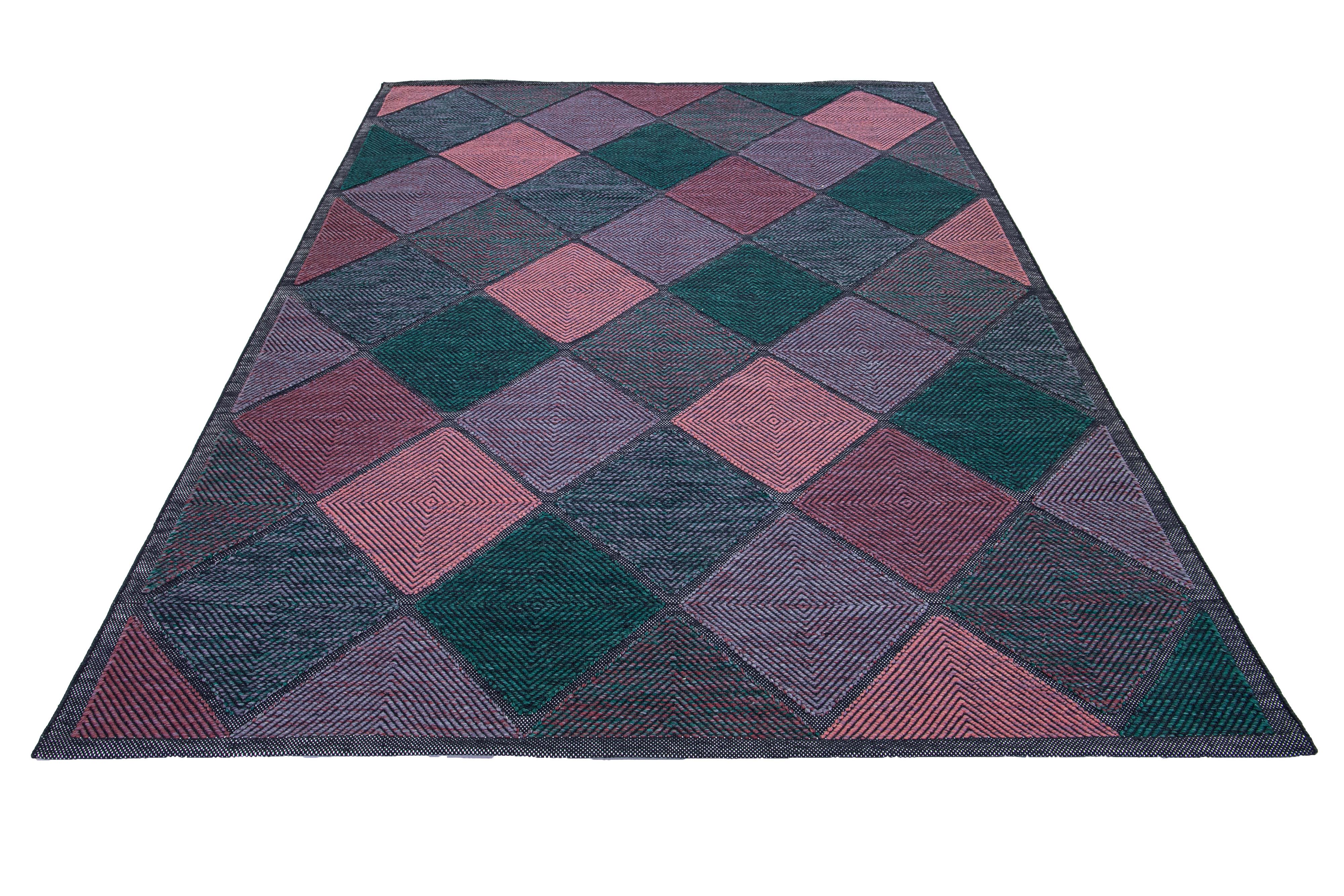 This flatweave rug showcases a contemporary Swedish design with a gray base. It's accented with green, purple, and pink geometric patterns throughout

 This rug measures 9'4