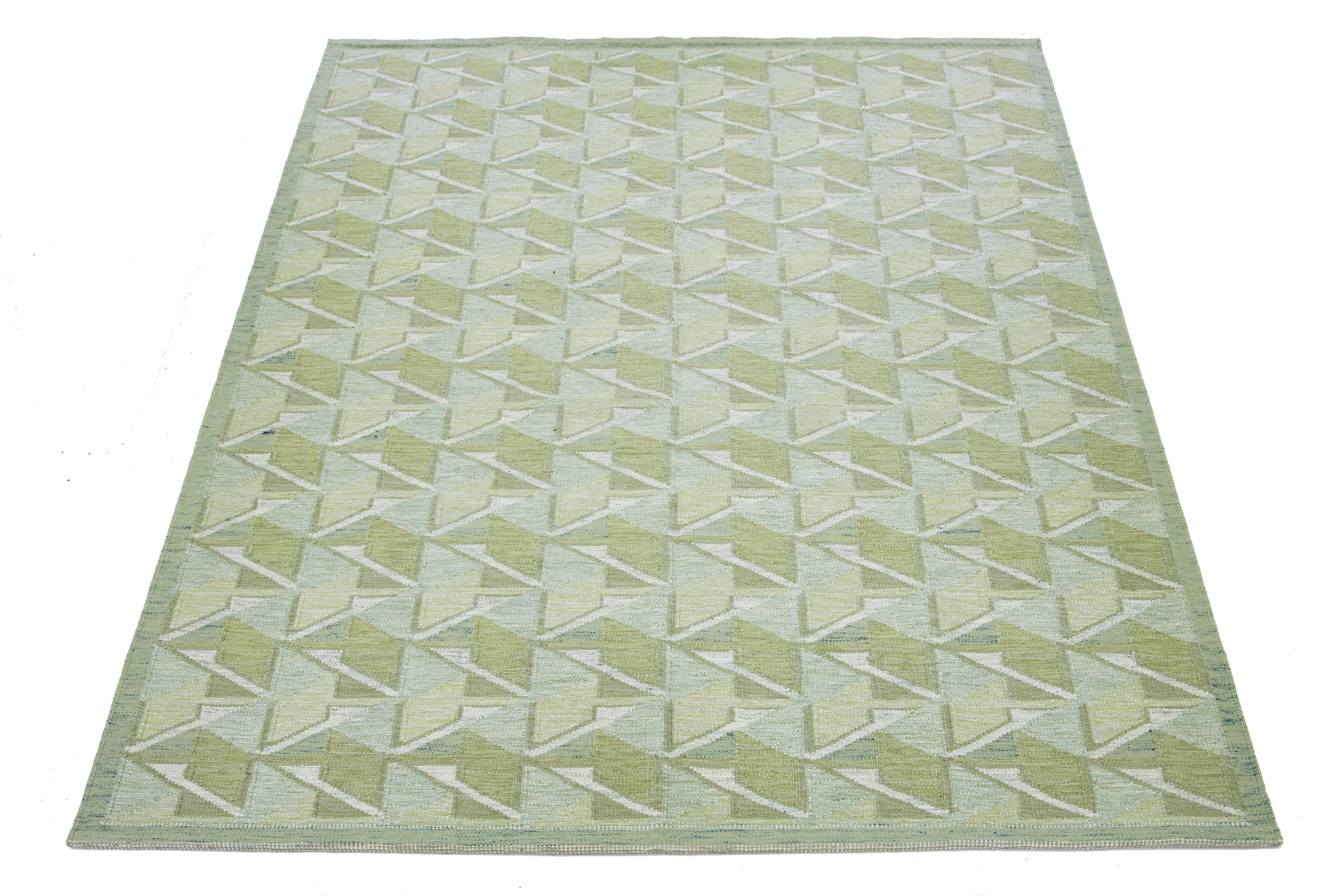 This flatweave rug showcases a contemporary Swedish design with a green base. It's accented with ivory geometric patterns throughout

 This rug measures 10' x 14'.

Our rugs are professionally cleaned before shipping.