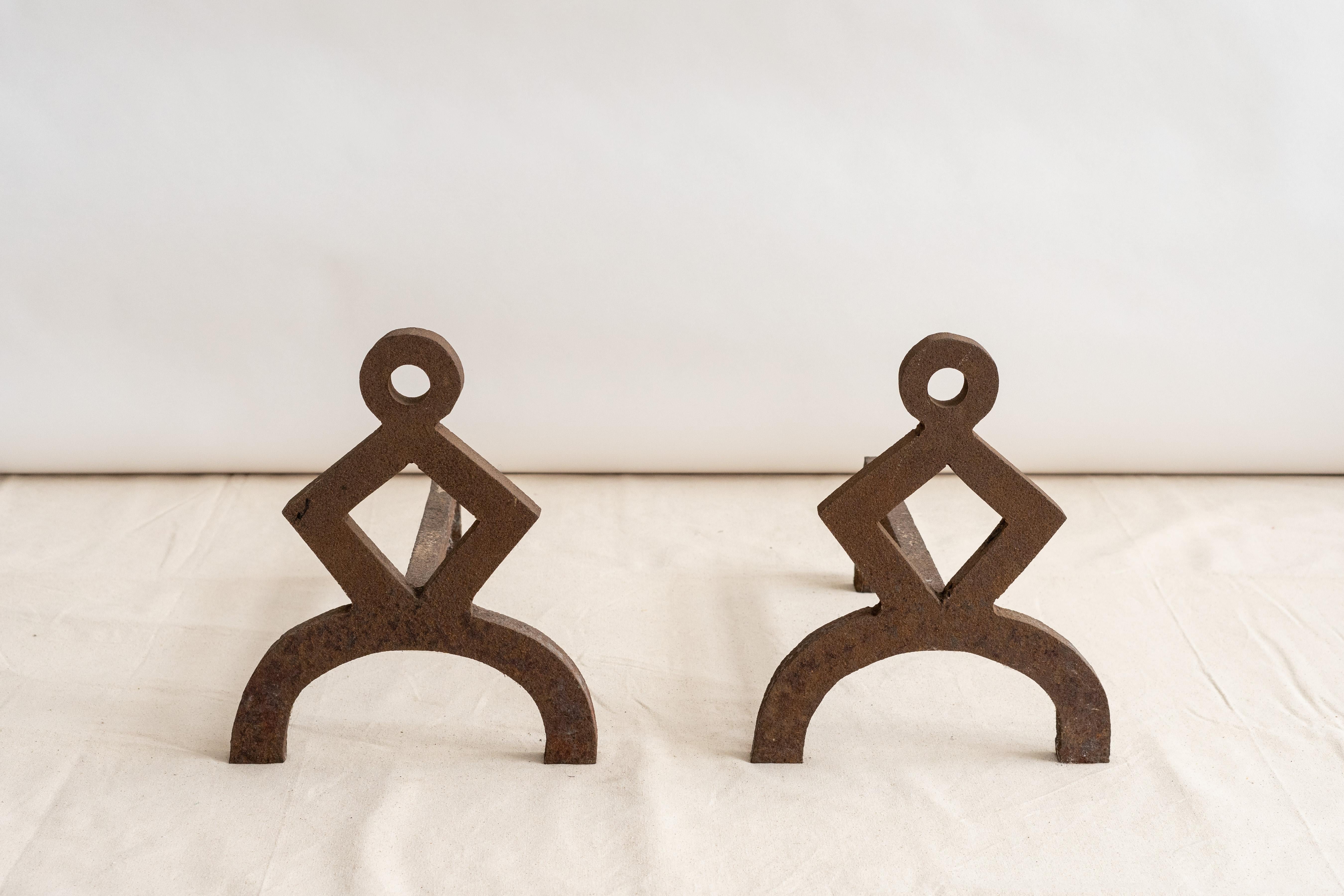 USA, ca. early 20th century. An unusual pair of andirons with strong geometric form. Each features heavy iron construction with appealing handmade look that would work well in a variety of interiors. While we do not know the maker or designer, we