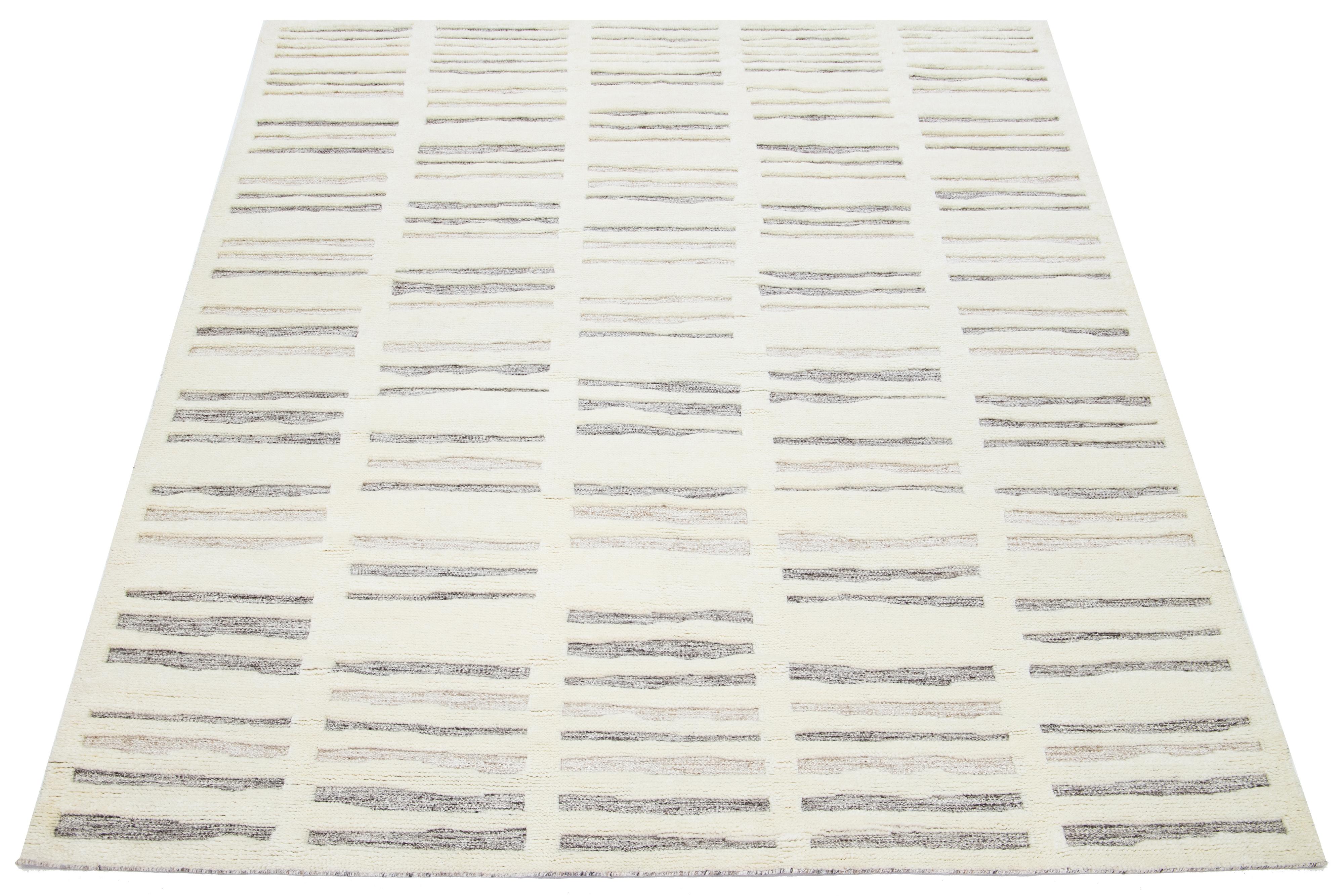 This Moroccan-style wool rug is hand-knotted and showcases a beautiful modern design with a natural ivory field. It features a stunning striped pattern in gray and brown.

This rug measures 8' x 10'.