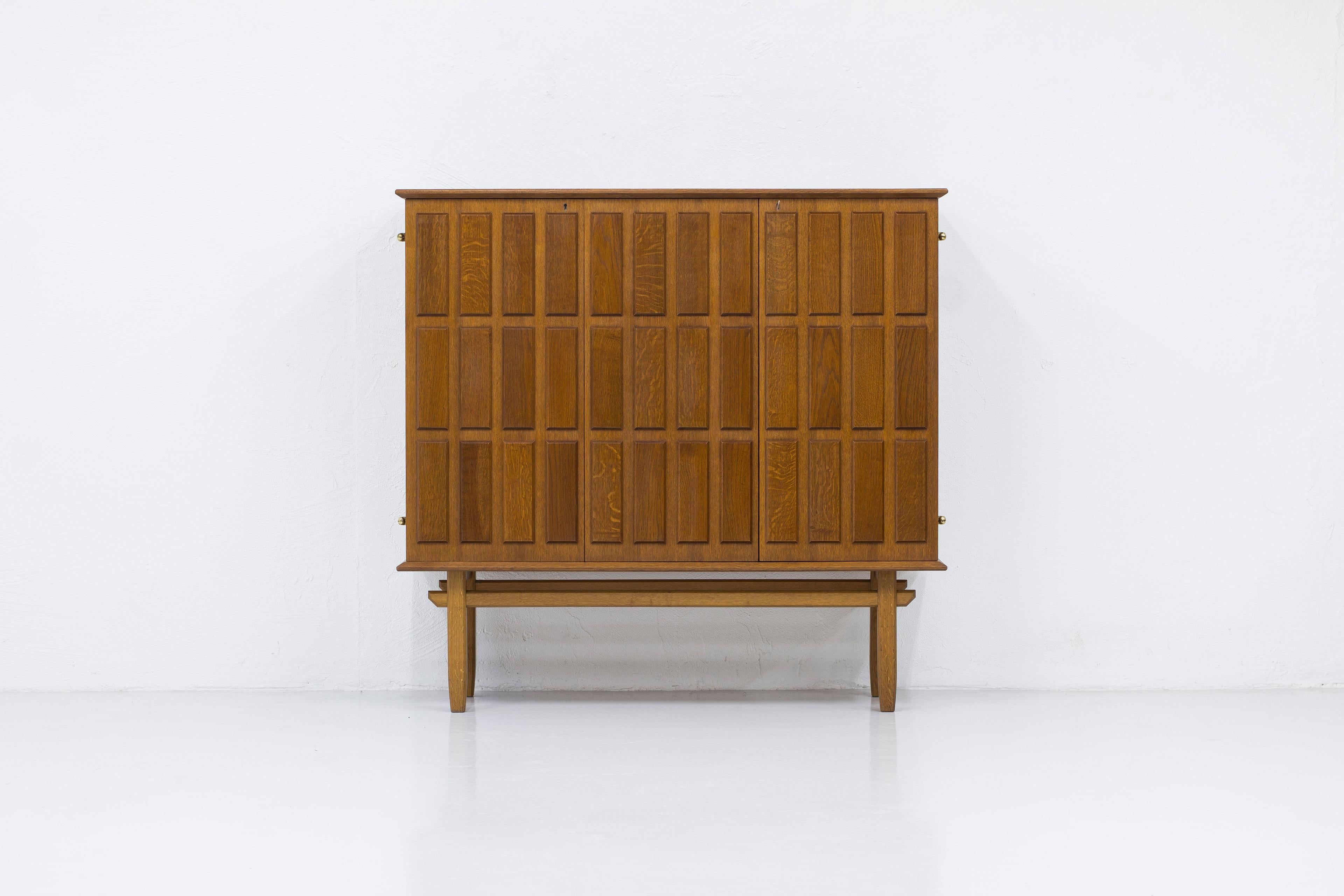 Swedish modern cabinet designed by Eyvind Beckman. Produced in Sweden by his own company during the 1940-50s. Made from oak with inside of Mahogny. Striking geometric relief pattern on the doors. Nice brass hinges and key. Four drawers with green