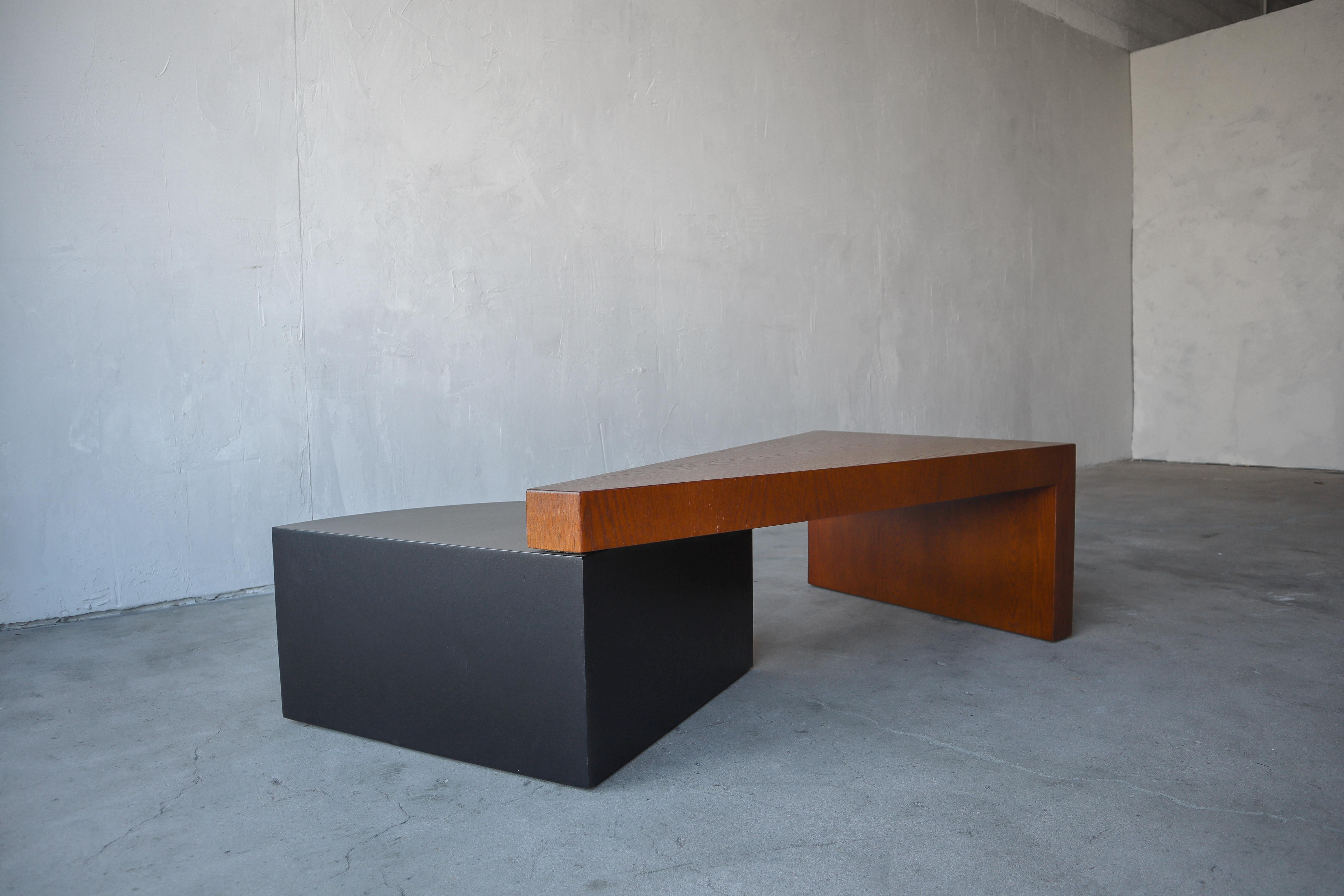 Great example of a post modern wood coffee table. Table is 2 tiered, comprised of a waterfalling triangular top supported at the opposite end by a lower tiered 1/4 circle drum. The entire table is oak, including the black drum. A very unique piece,