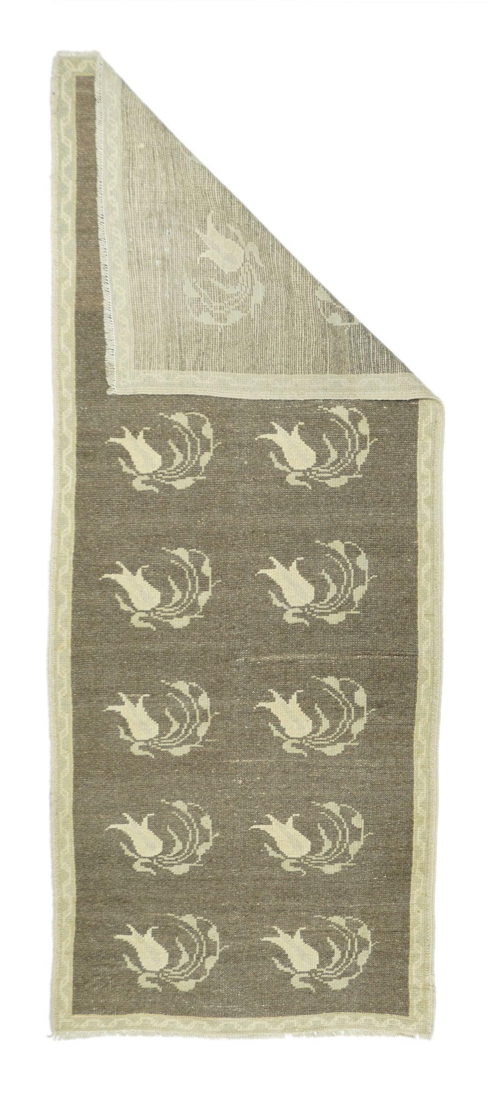 Geometrischer Teppich 2'9'' x 6'9''. Das abgewetzte ziegelrote Feld zeigt zwei Säulen mit je sieben einzelnen, elegant gewirbelten Tulpen und dazugehörigen Stängeln. Interne Details des Schattens. Beige und strohfarbene schmale Bordüre mit