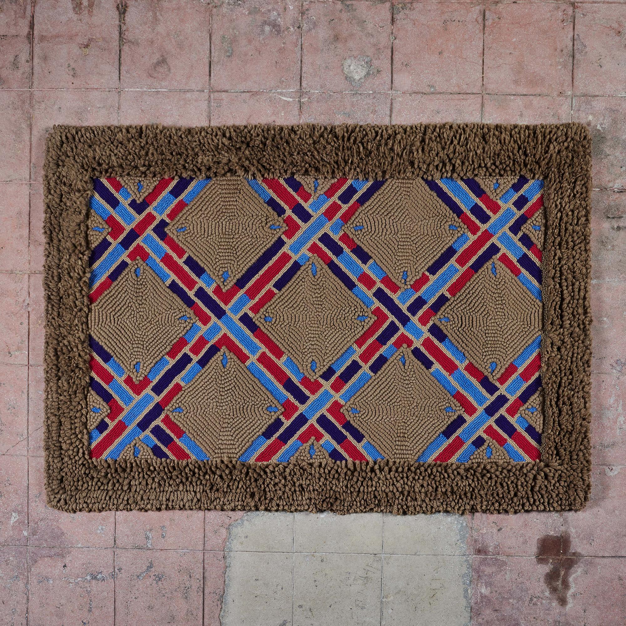 Rectangular rug made of hand-looped wool. It features a geometric pattern of diamonds and rectangles in tan, blue, red and black. The rug is outlined in a high pile tan shag wool.

Dimensions
73