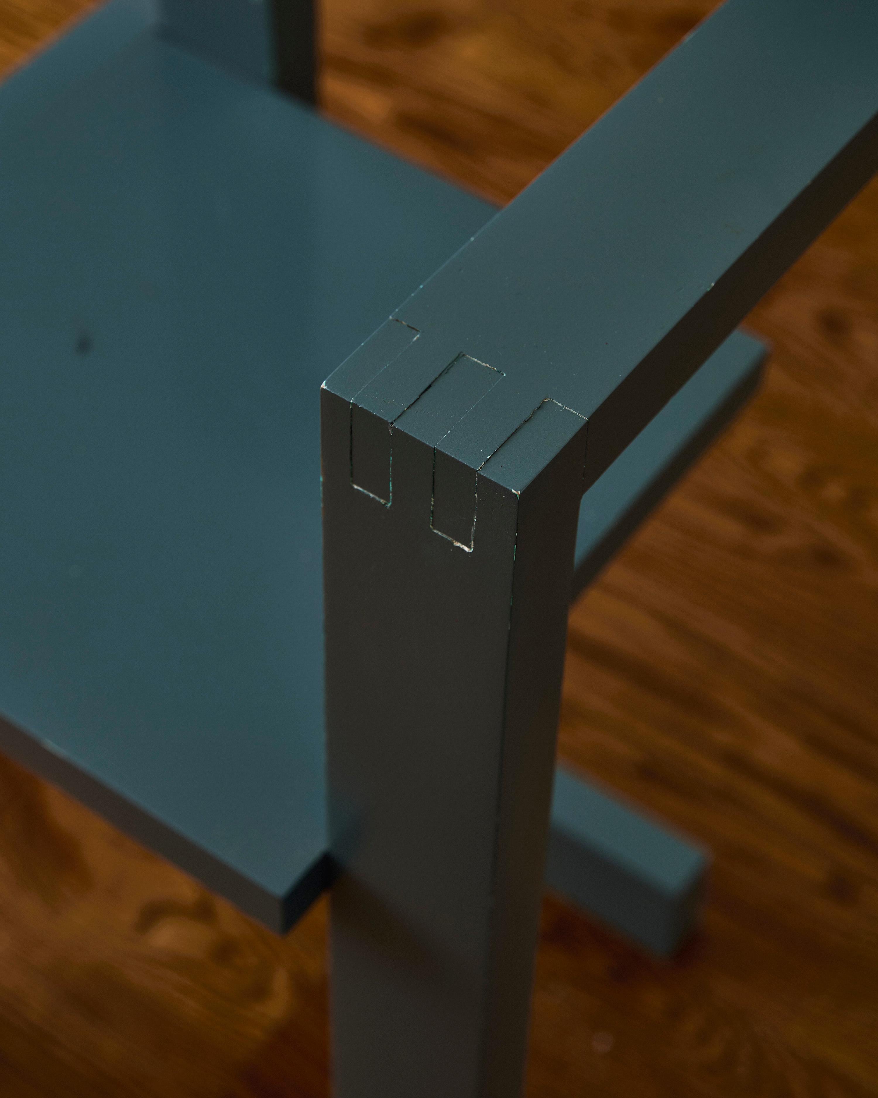 Sedia geometrica alla maniera della sedia Steltman di Gerrit Rietveld, dipinta in grigio con proporzioni più piccole rispetto al progetto originale.