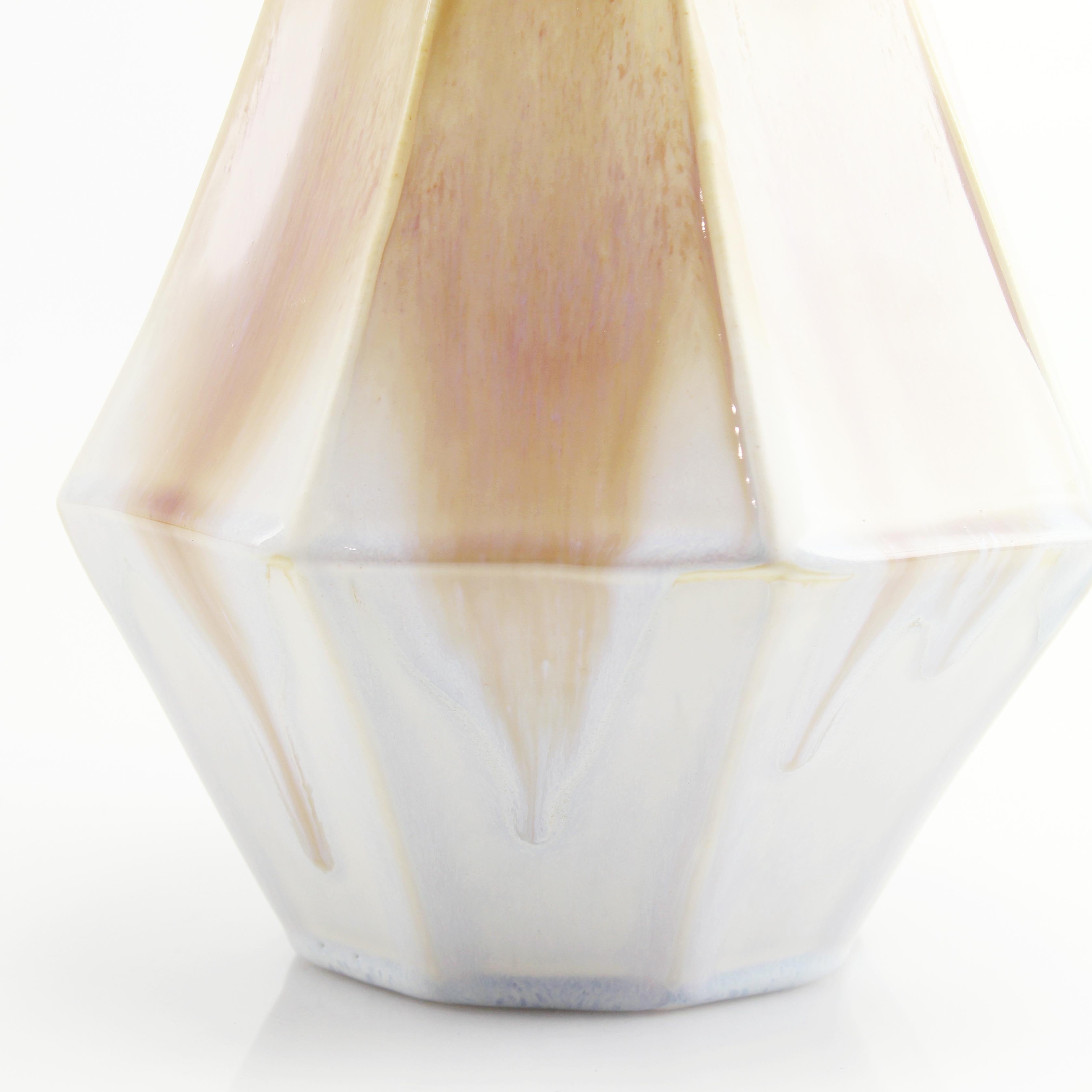 The clean, modern design of the geometric statement vase offers an updated, elegant look to your room with a Mid-Century Modern feel. This one of a kind piece features a crystalline sandstone glaze with a blush ombre effect. Add a large arrangement