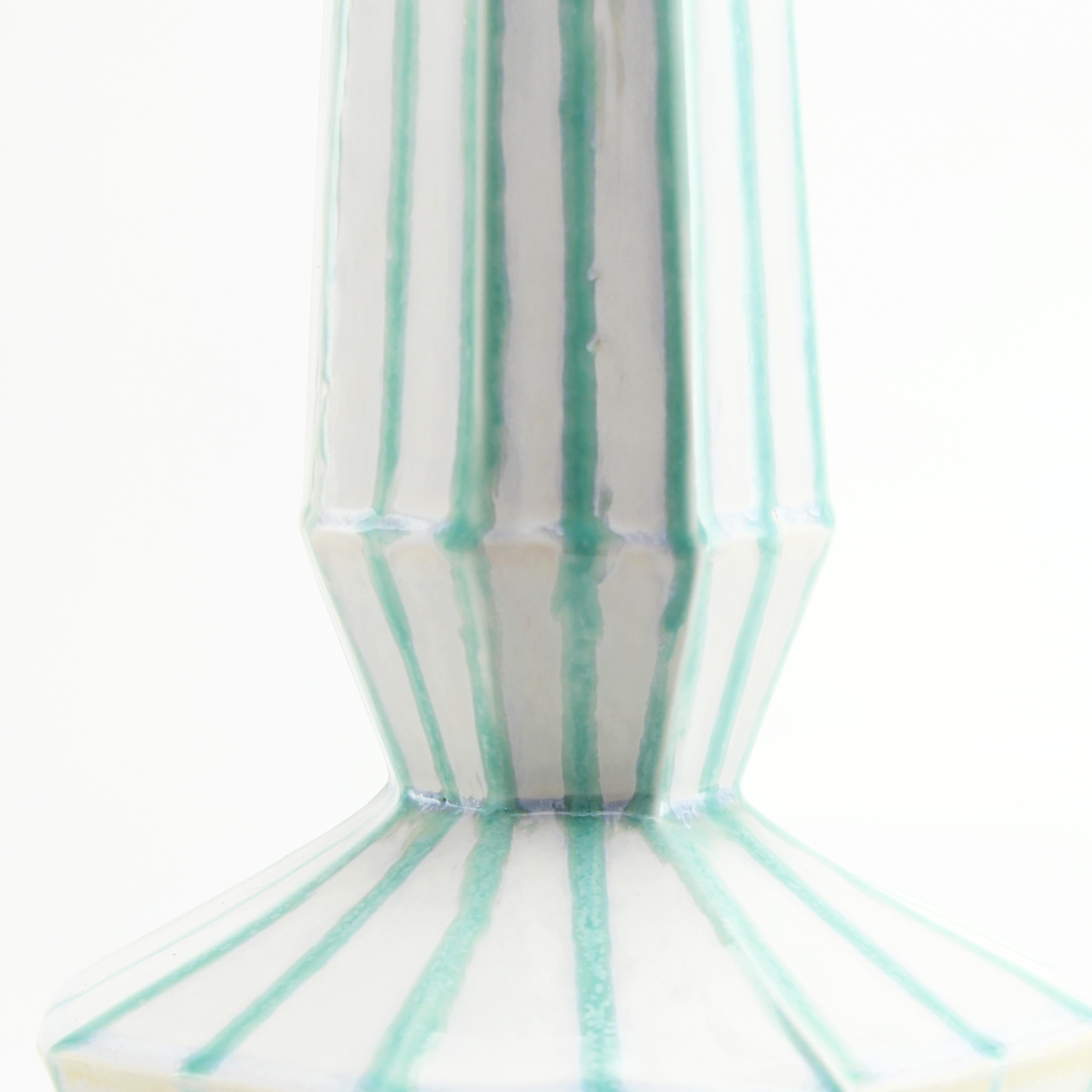 The clean, modern design of the geometric statement vase offers an updated, elegant look to your room with a Mid-Century Modern feel. This one of a kind vase features a modern stripe glaze to highlight the clean faceted design. Add a large