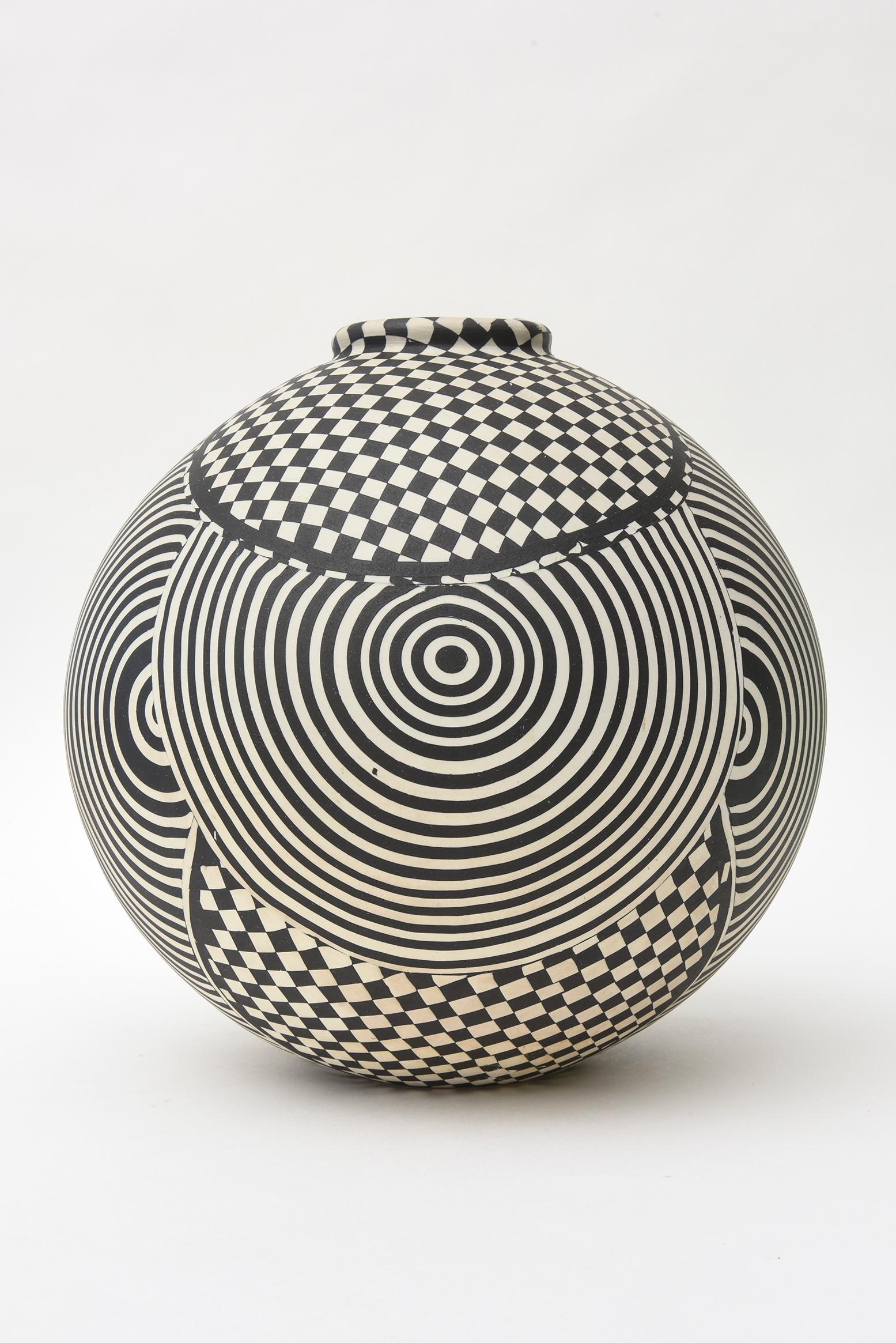 This graphic black and white geometric hand painted studio one of kind op art ceramic bowl, vessel or sculpture is mesmerizing. It is bulbous and makes a splashing presence. It is in the style and influence of Victor Vasarely. It is vintage and from