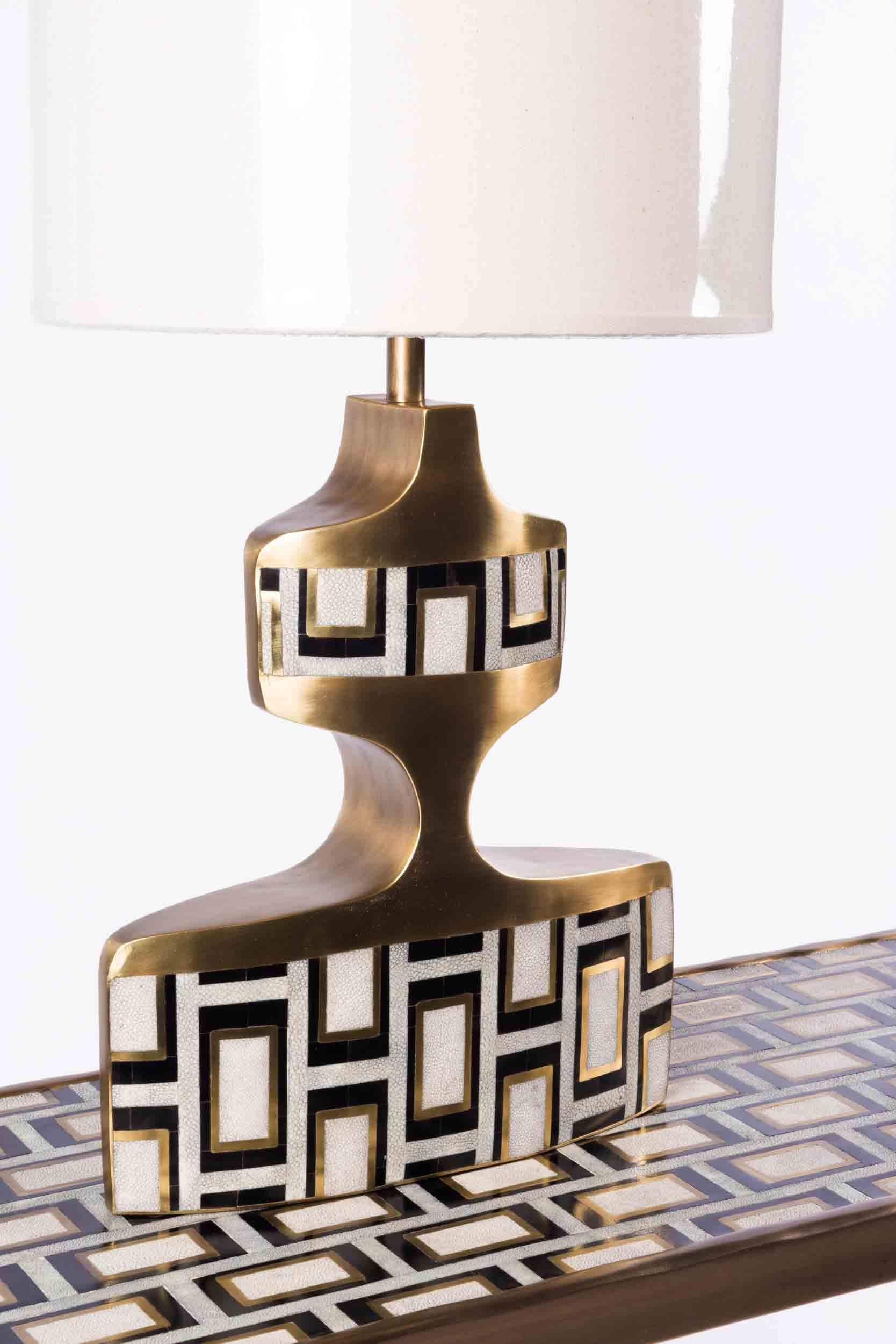 Die geometrische Lampe ist ein skulpturales Stück mit schönen Einlegearbeiten. Diese Tischleuchte zeichnet sich durch ein kühnes Blockmuster in einer Mischung aus cremefarbenem Chagrin, schwarzer Federschale und bronzefarbenem patiniertem Messing