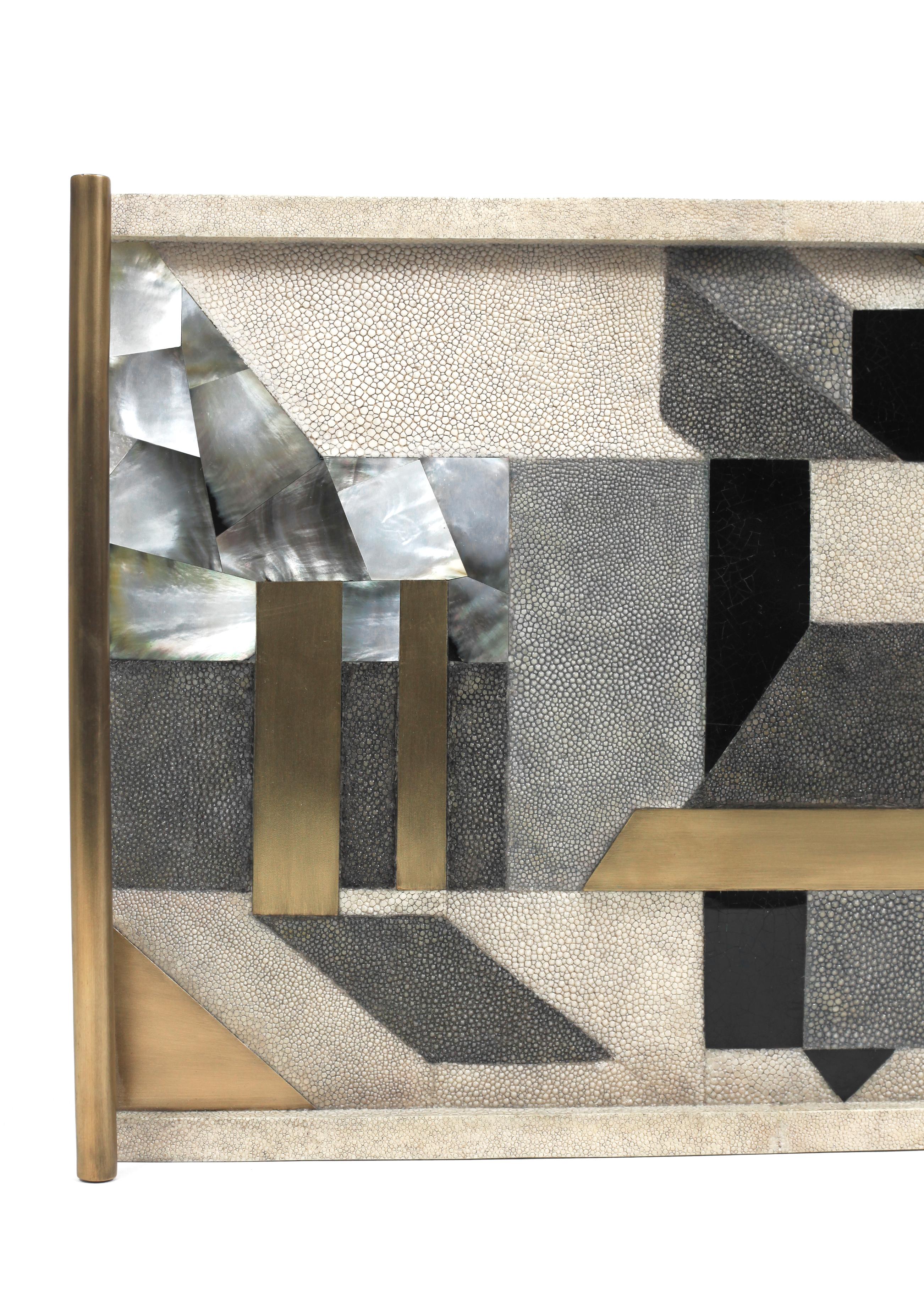 Un plateau rectangulaire classique revisité ; ce plateau géométrique de Kifu Paris incrusté d'un mélange de galuchat, de coquillages et de laiton bronze-patina, constitue une pièce de table étonnante dans n'importe quel espace. La poignée en laiton