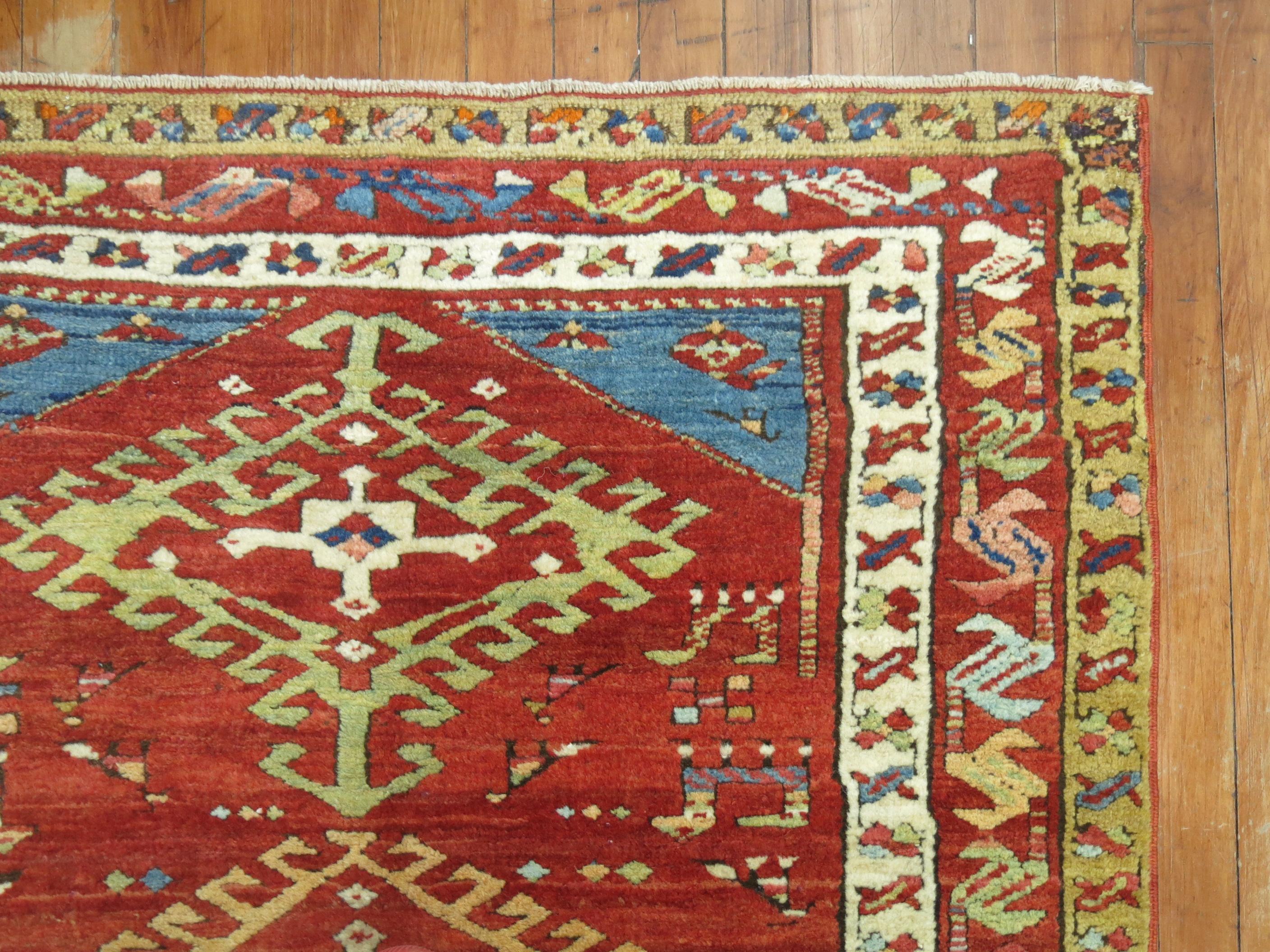 Full pile geometric antique northwest Persian runner with a red field bodied by colorful medallions, multiple borders and French blue corner spandrels, circa 1920.

Measures: 3'6” x 9'6”.