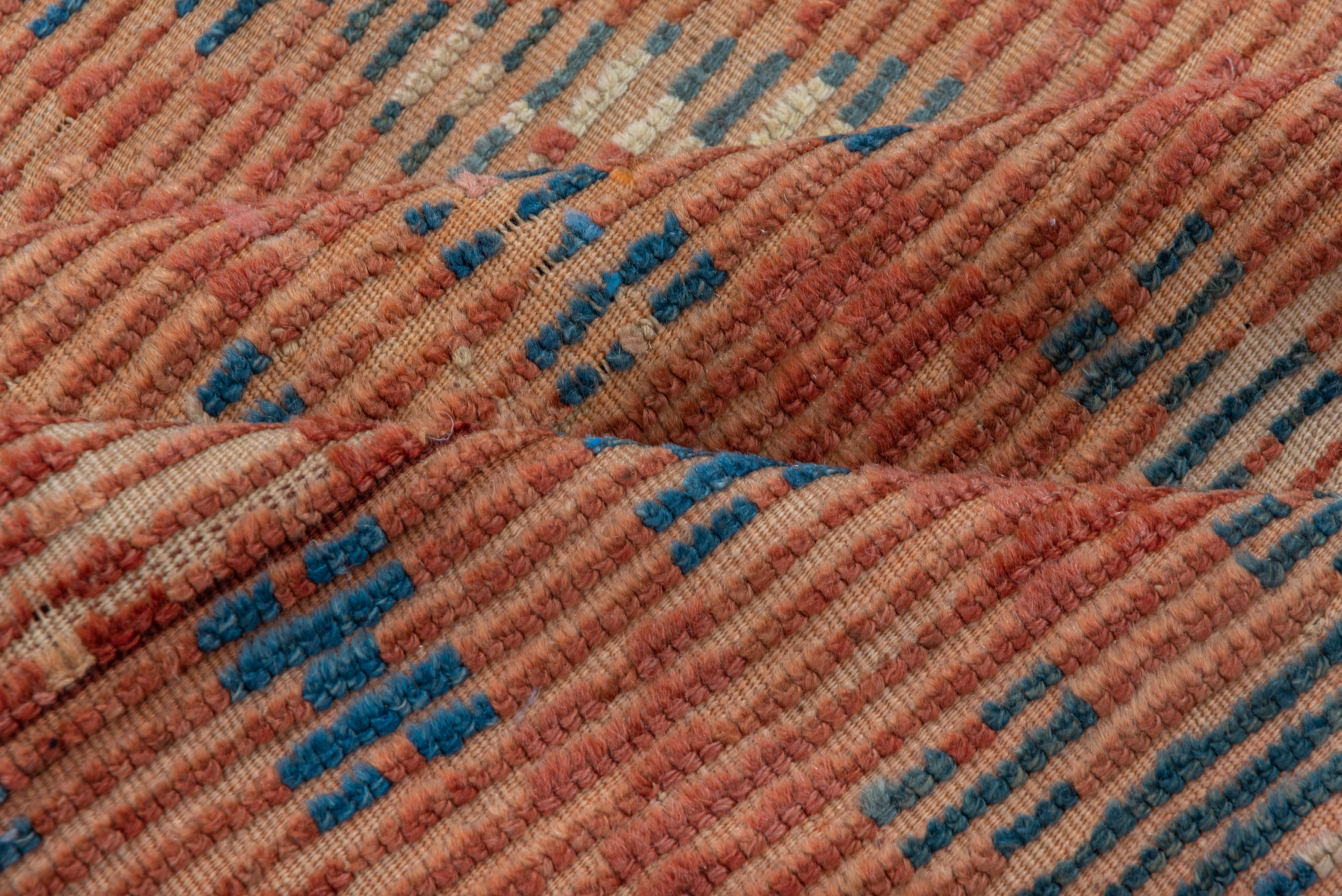 Ce tapis de village très détaillé à motif de treillis présente des tons orange brûlé et des bleus poudrés doux, semblables à la première lumière avant le lever du soleil. 