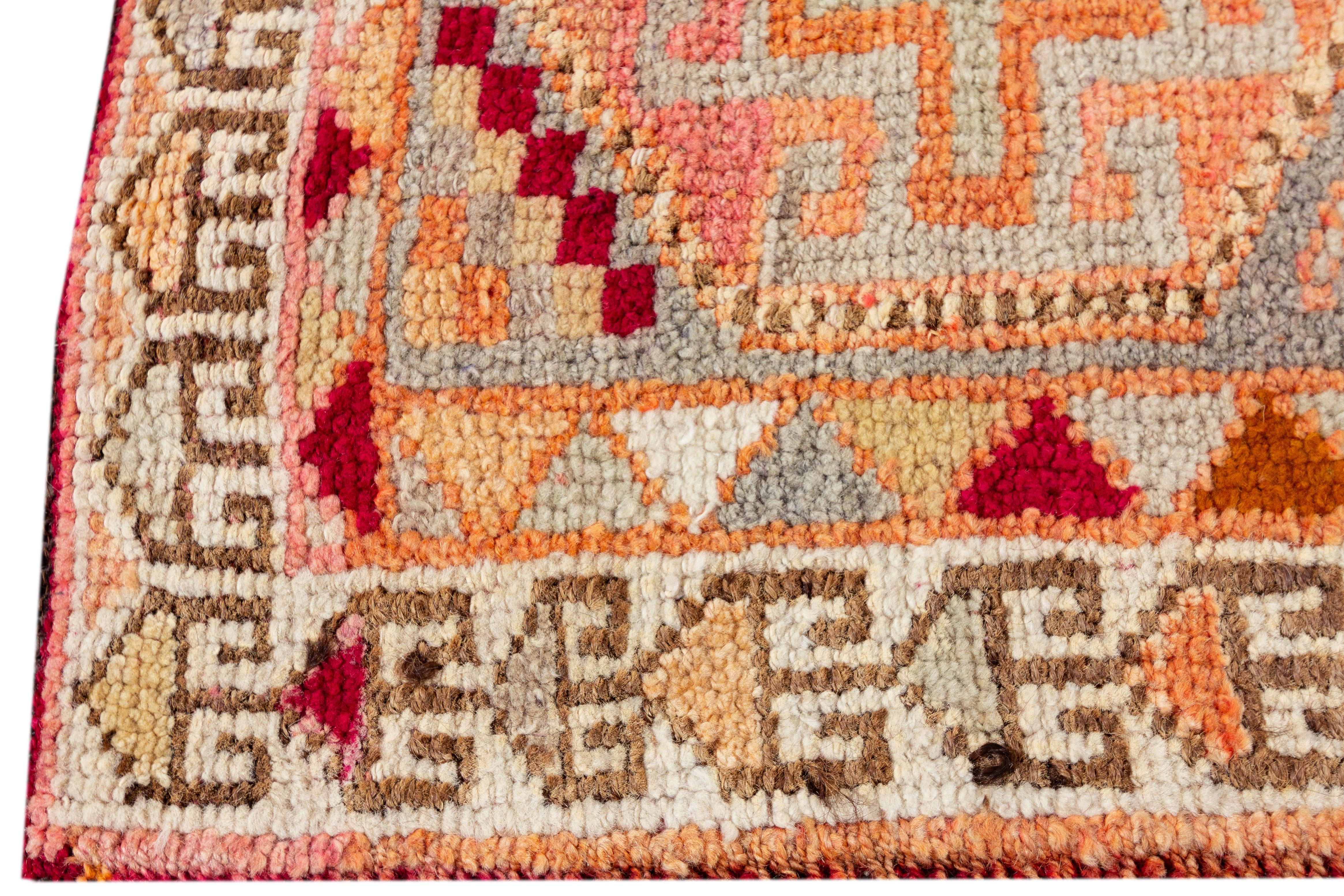 Ein alter türkischer Wollteppich aus Anatolien aus dem 20. Jahrhundert mit einem geometrischen Allover-Muster, das mit lebhaften mehrfarbigen Akzenten auf einem grauen und pfirsichfarbenen Feld verziert ist.

Dieser Teppich misst 3'1