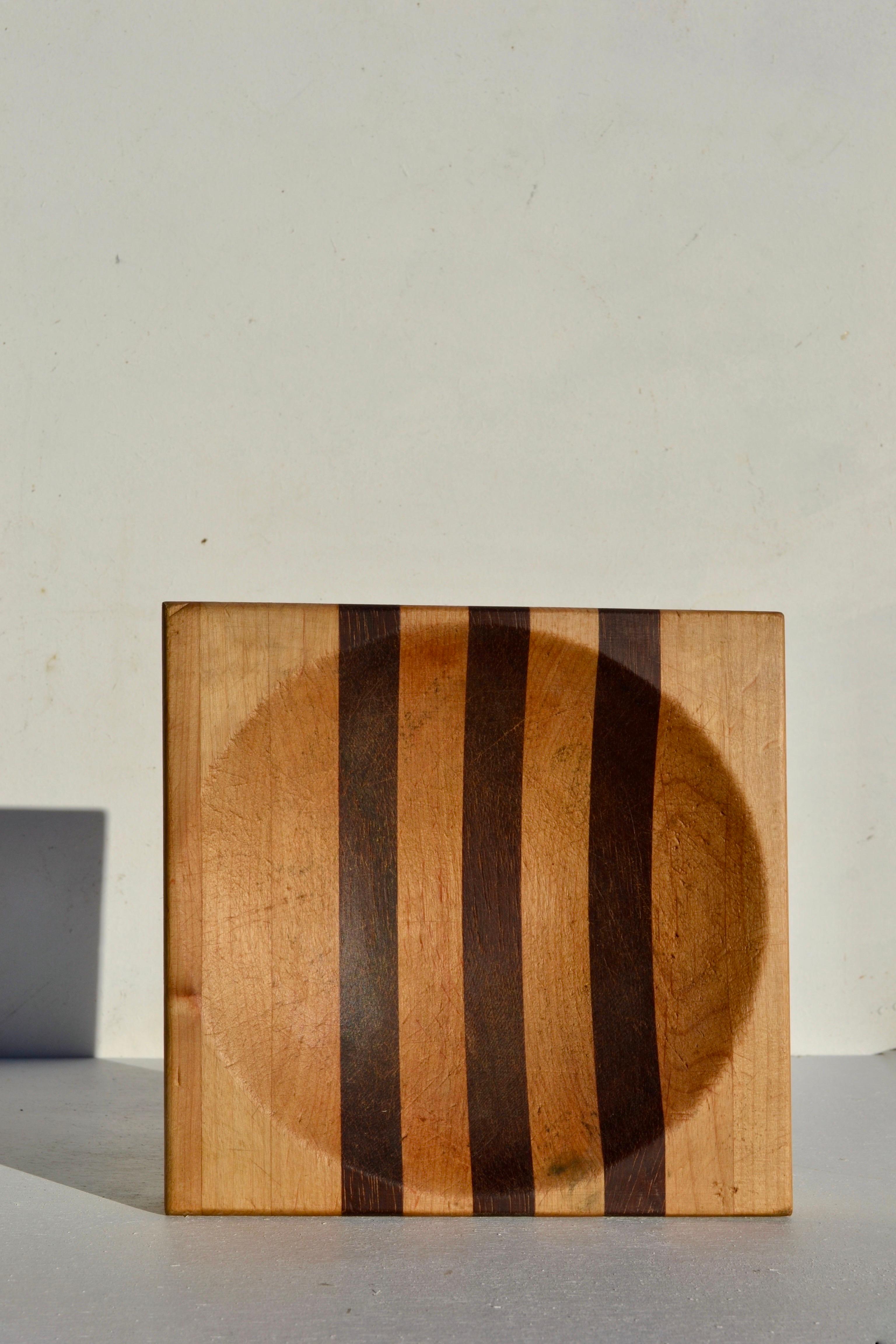 
Eleganza di un portaoggetti in legno composto da strisce laminate di varie specie di legno, incollate con precisione e poi intagliate da un unico blocco. Il gioco di toni chiari e scuri mette in risalto la profondità scultorea del pezzo e riflette