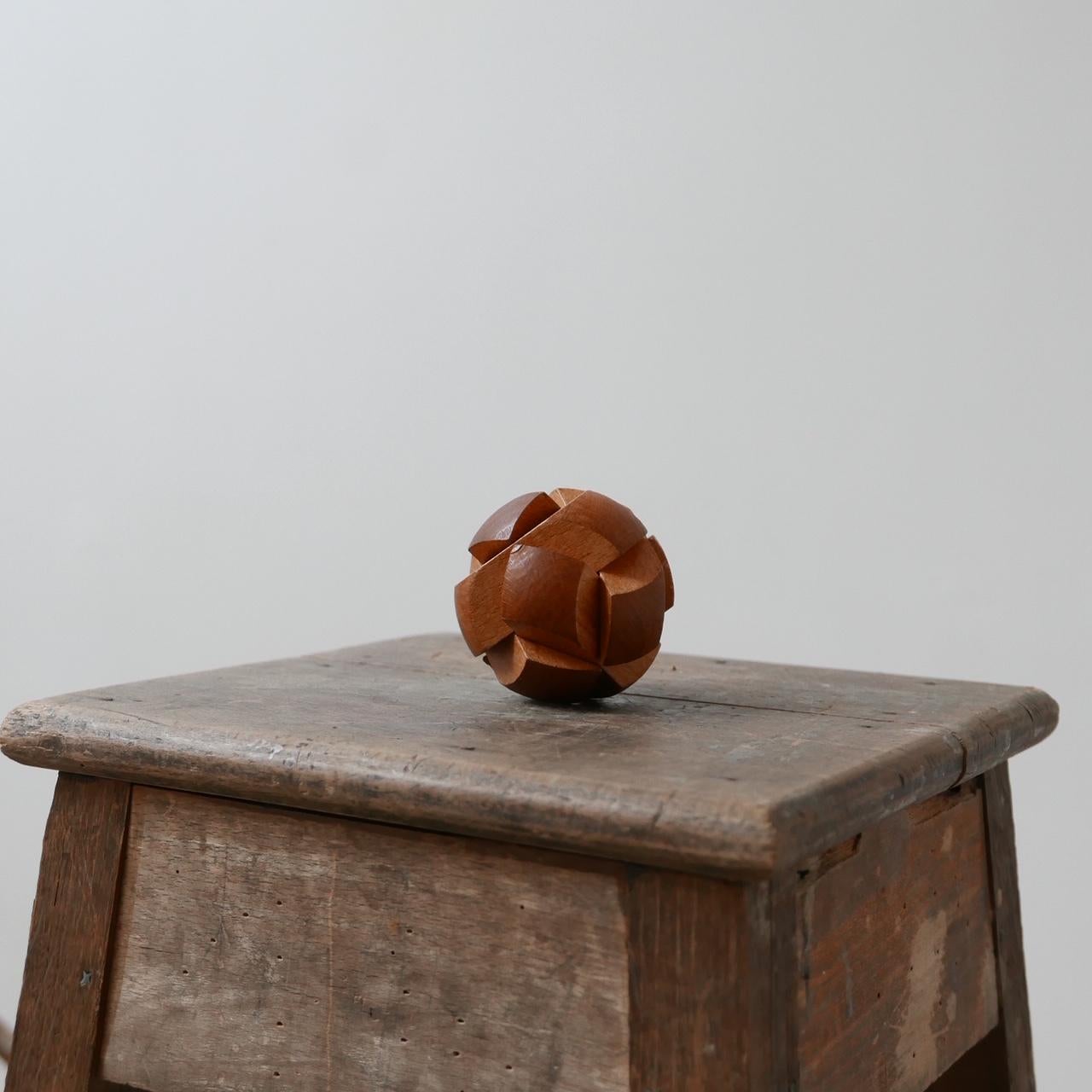 A teak puzzle sculpture ball.

English, circa 1970s.

Great desk or shelf curio. Very tactile.

Dimensions: 8 cm diameter.
 