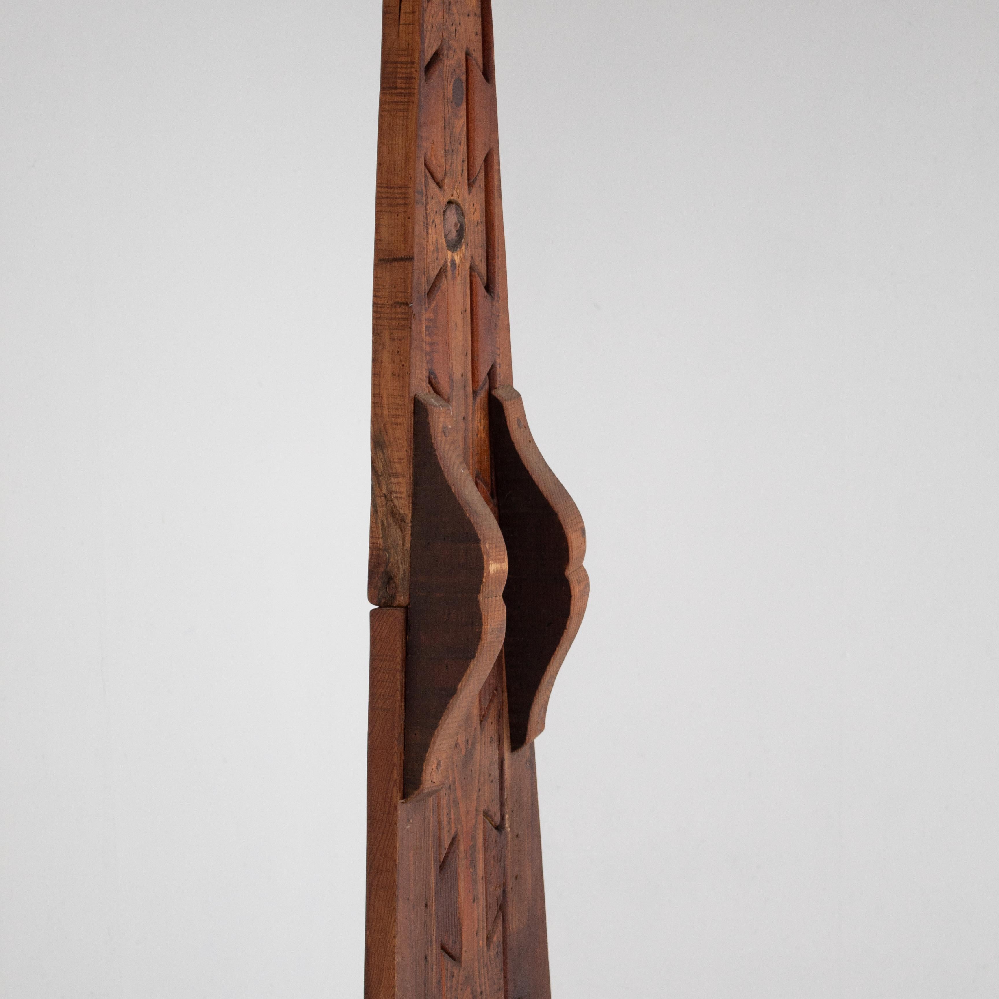 Questa scultura d'arte in legno di Luciano Bertolotto mostra il suo talento nel trasformare il legno grezzo in forme audaci ed espressive. La forma alta si erge con linee decise e dettagli intagliati che creano movimento e profondità. Il suo stile