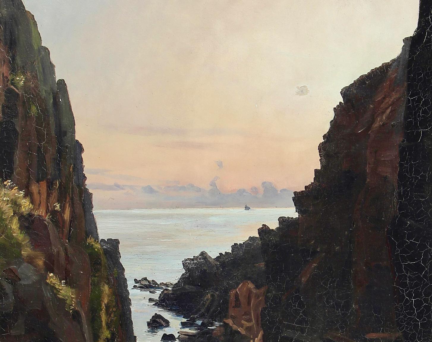 Sonnenuntergang am Kullen bei Mölle im äußersten Süden Schwedens. 
Zwischen zwei steilen Klippen breitet sich ein schmaler Steinstrand aus, von dem aus man einen ruhigen Blick über das stille Meer in Richtung Dänemark hat. Der Himmel ist in sanften