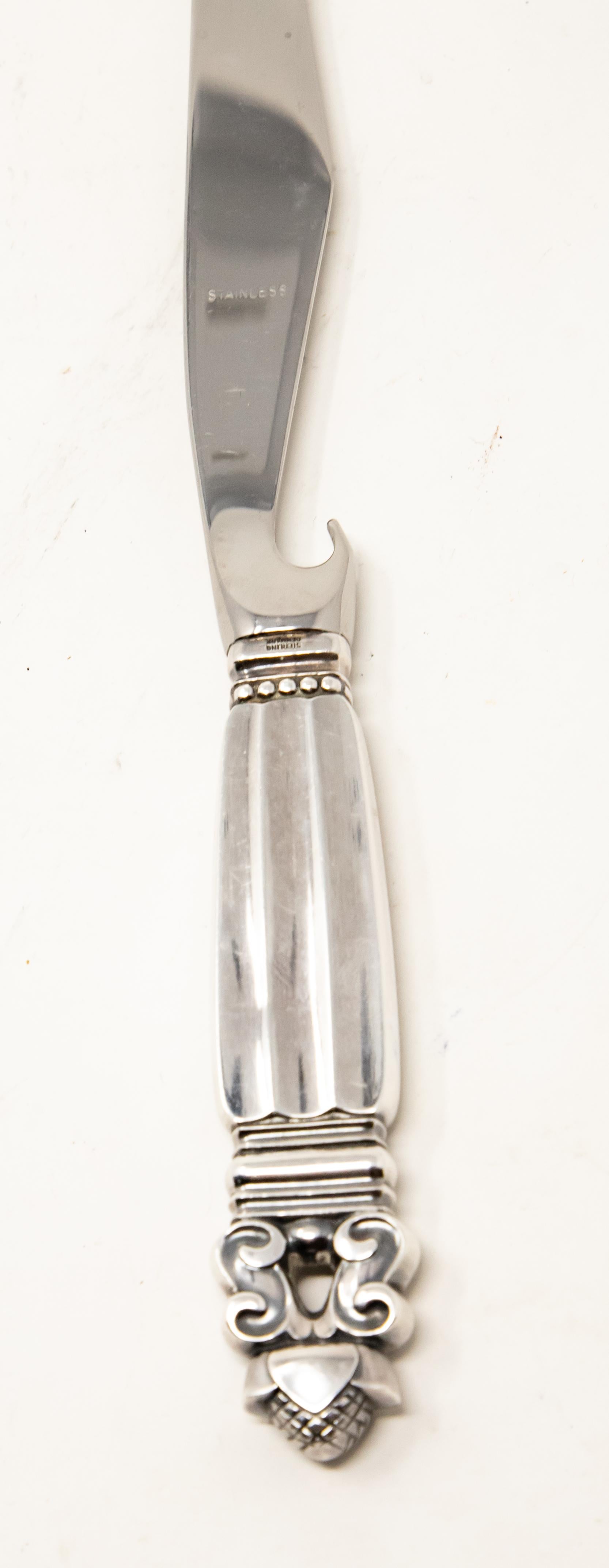 Offering this elegant Georg Jensen pronged bar knife. The pattern of the knife is acorn. The handle is marked Sterling, Denmark with a stainless blade. Has the bottle opener and pronged tip.