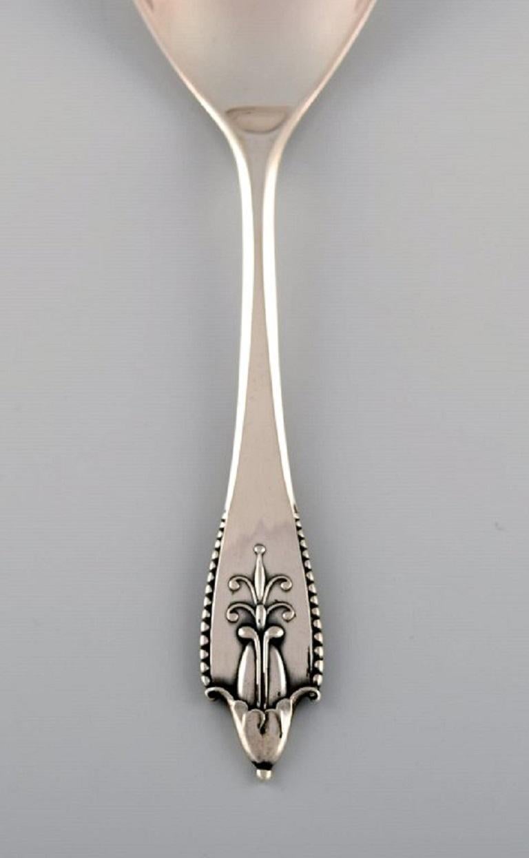 Georg Jensen Akkeleje serving spoon in silver 830. Ca. 1920.
Length: 19.5 cm.
Stamped.
In excellent condition.
Our skilled Georg Jensen silversmith / goldsmith can polish all silver and gold so that it looks like new. 
The price is very