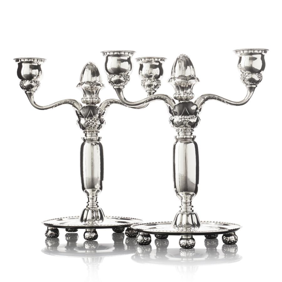 A pair of antique Danish silver Georg Jensen candelabra, design #93 by Georg Jensen in 1918. The meticulous silversmithing showcased in these candelabra is truly remarkable, adorned with an abundance of intricately chased floral motifs and delicate