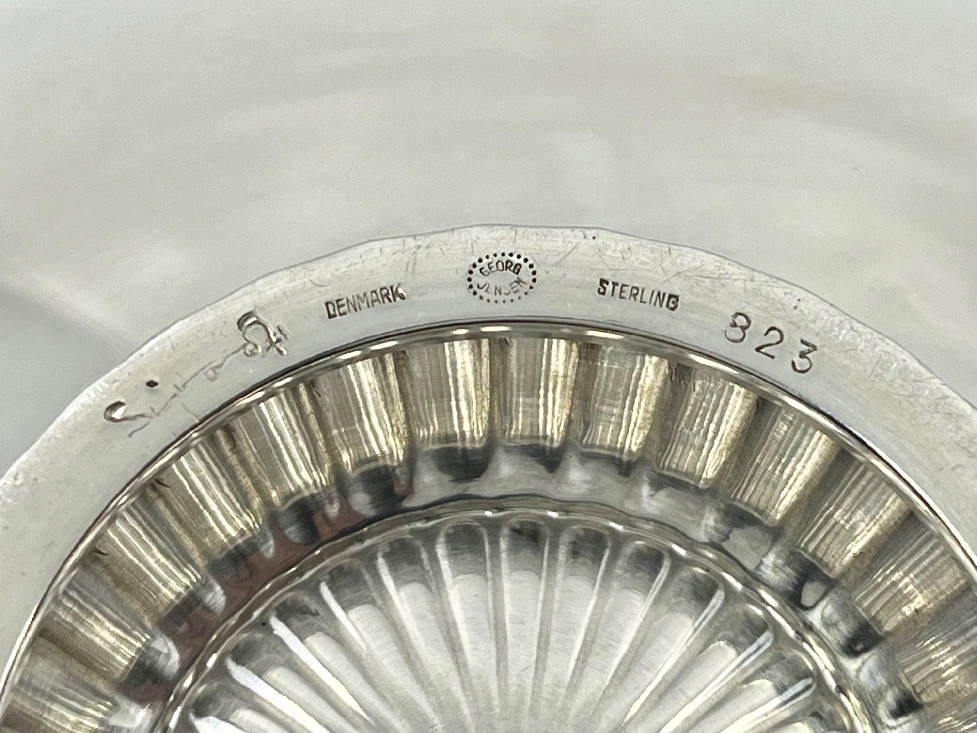 A sterling silver Georg Jensen Art Deco bowl, design #823 by Sigvard Bernadotte from 1938. A plain bowl standing on a small crimped foot, inside the bowl is a round hand-chased japanesque motif.

Additional information:
Material: Sterling