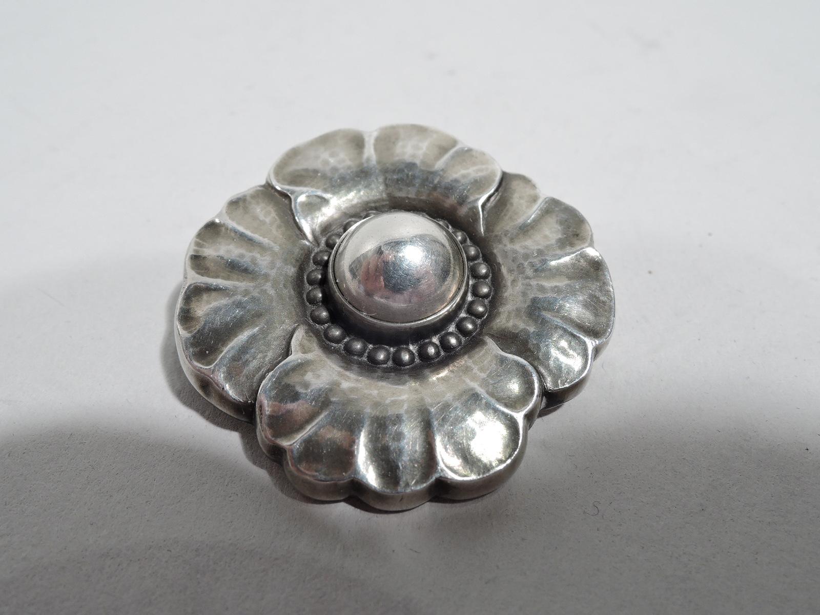 Art Nouveau sterling silver flower brooch. Made by Georg Jensen in Copenhagen. Beaded cabochon center and irregularly scalloped hand-hammered petals. The all-silver version of the master’s design. Cited in: Drucker. Georg Jensen, 1997, p. 168. Fully